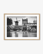 Framed black and white photo of a city street with a windmill, cars, and buildings.