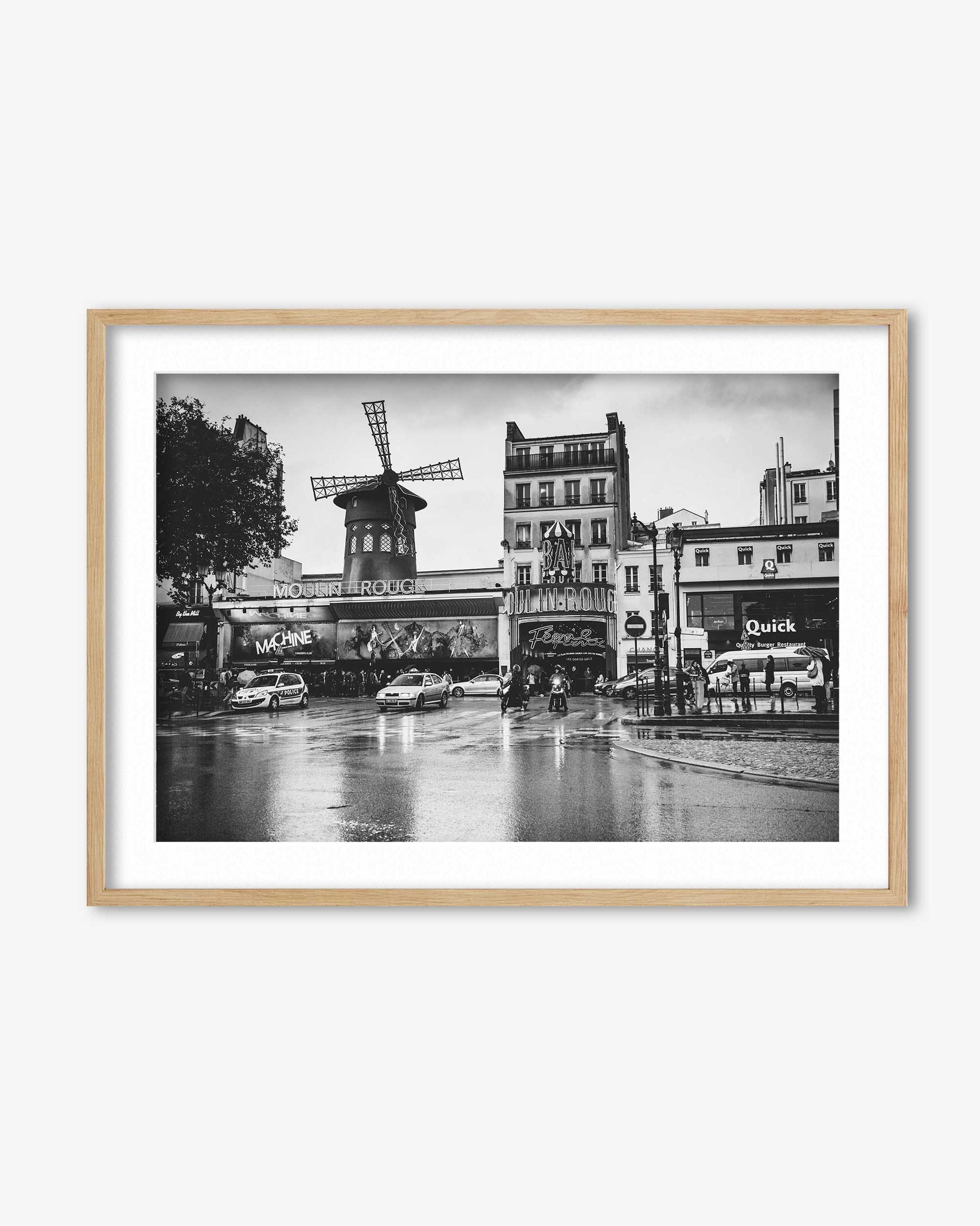 Framed black and white photo of a city street with a windmill, cars, and buildings.