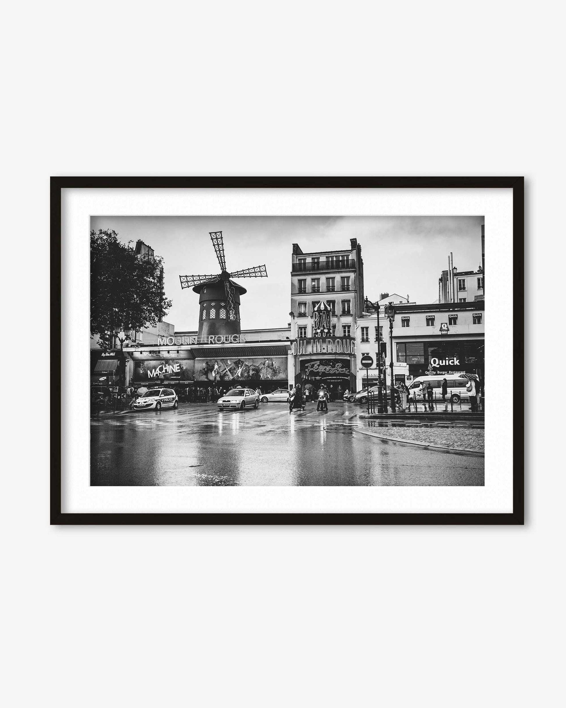 Framed black and white photograph of a city street with a windmill, cars, and buildings.
