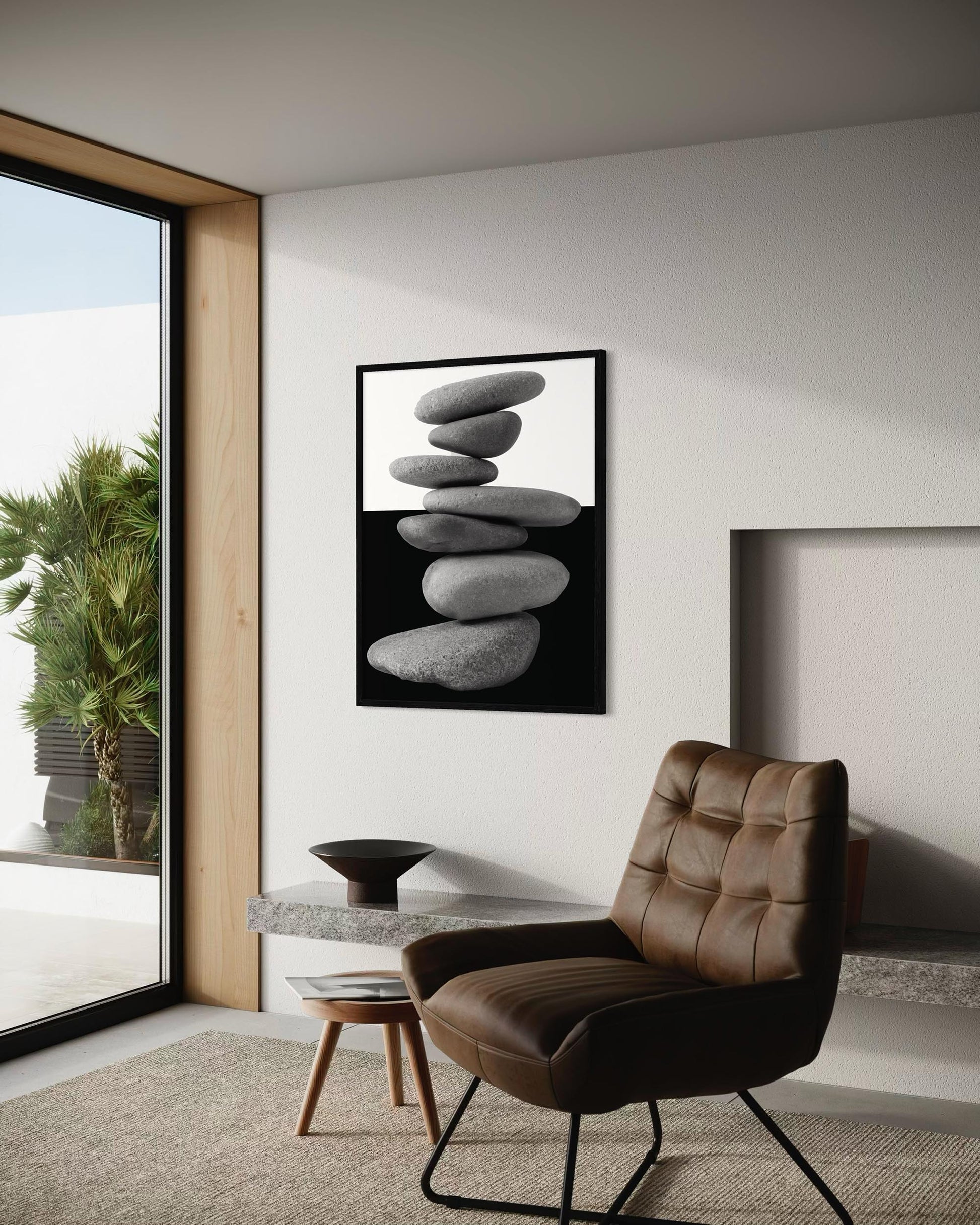 Modern interior with a brown leather chair, small table, and framed artwork of stacked stones.