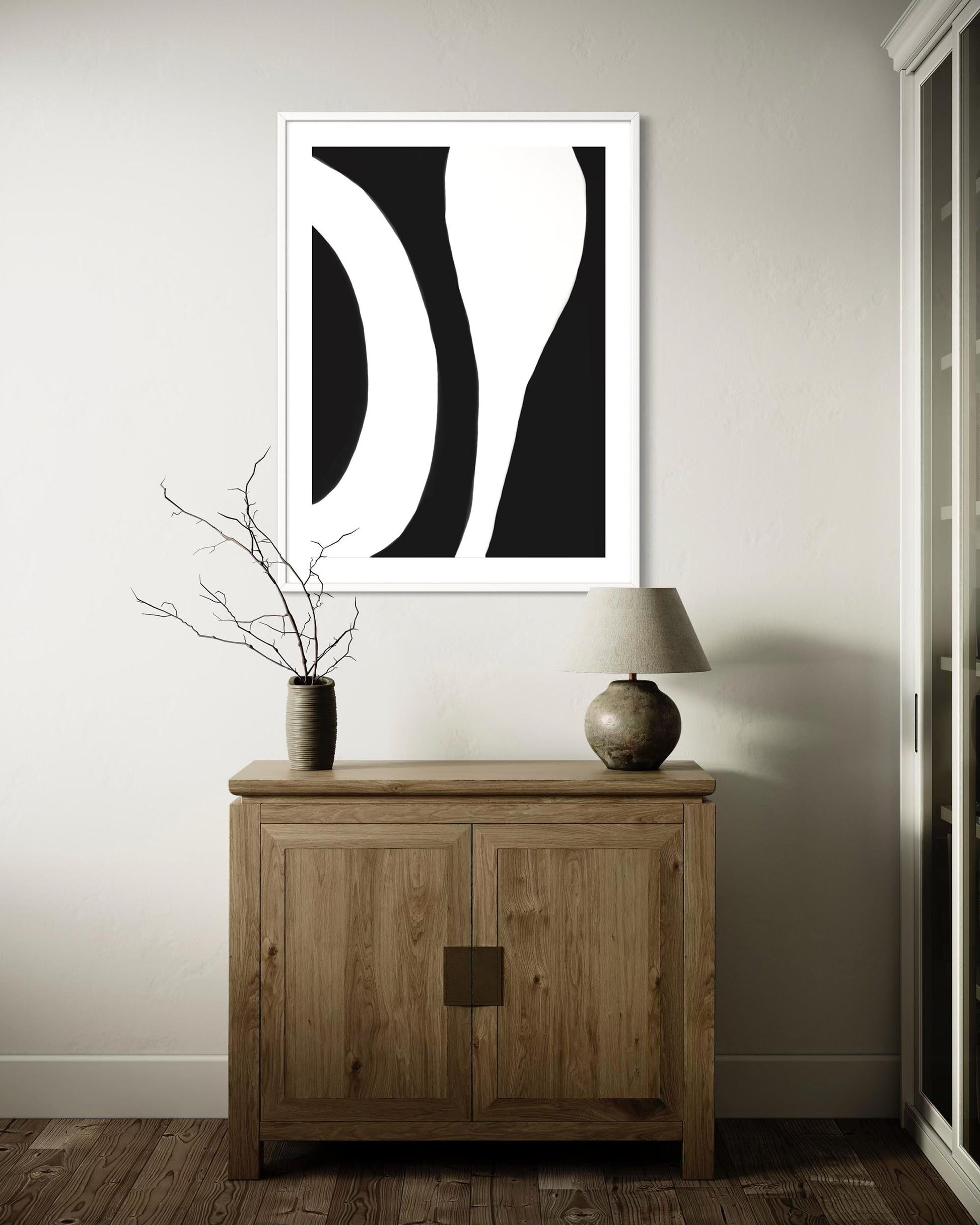 Abstract black and white artwork on a wall above a wooden cabinet.