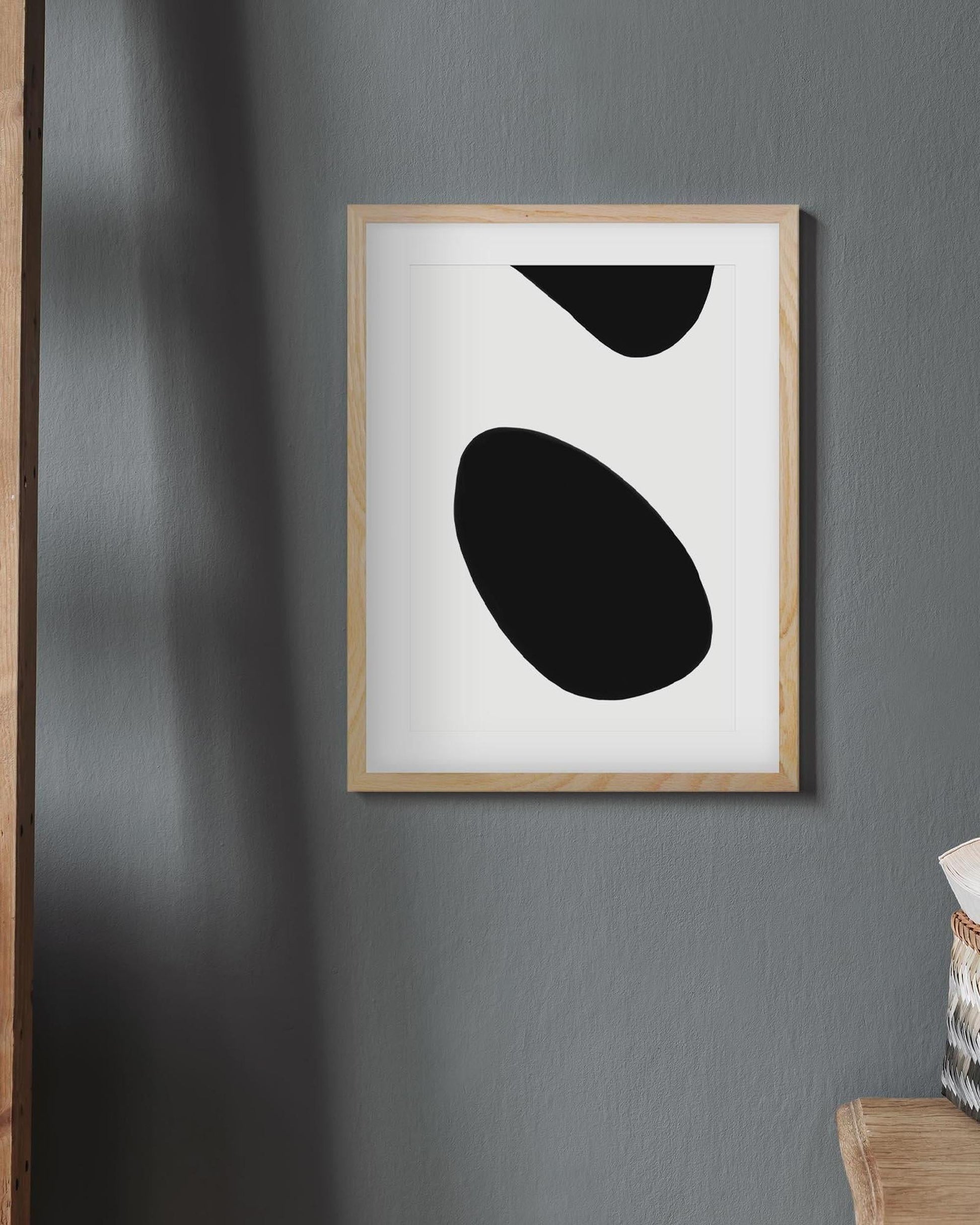 Framed abstract art with black shapes on a gray wall