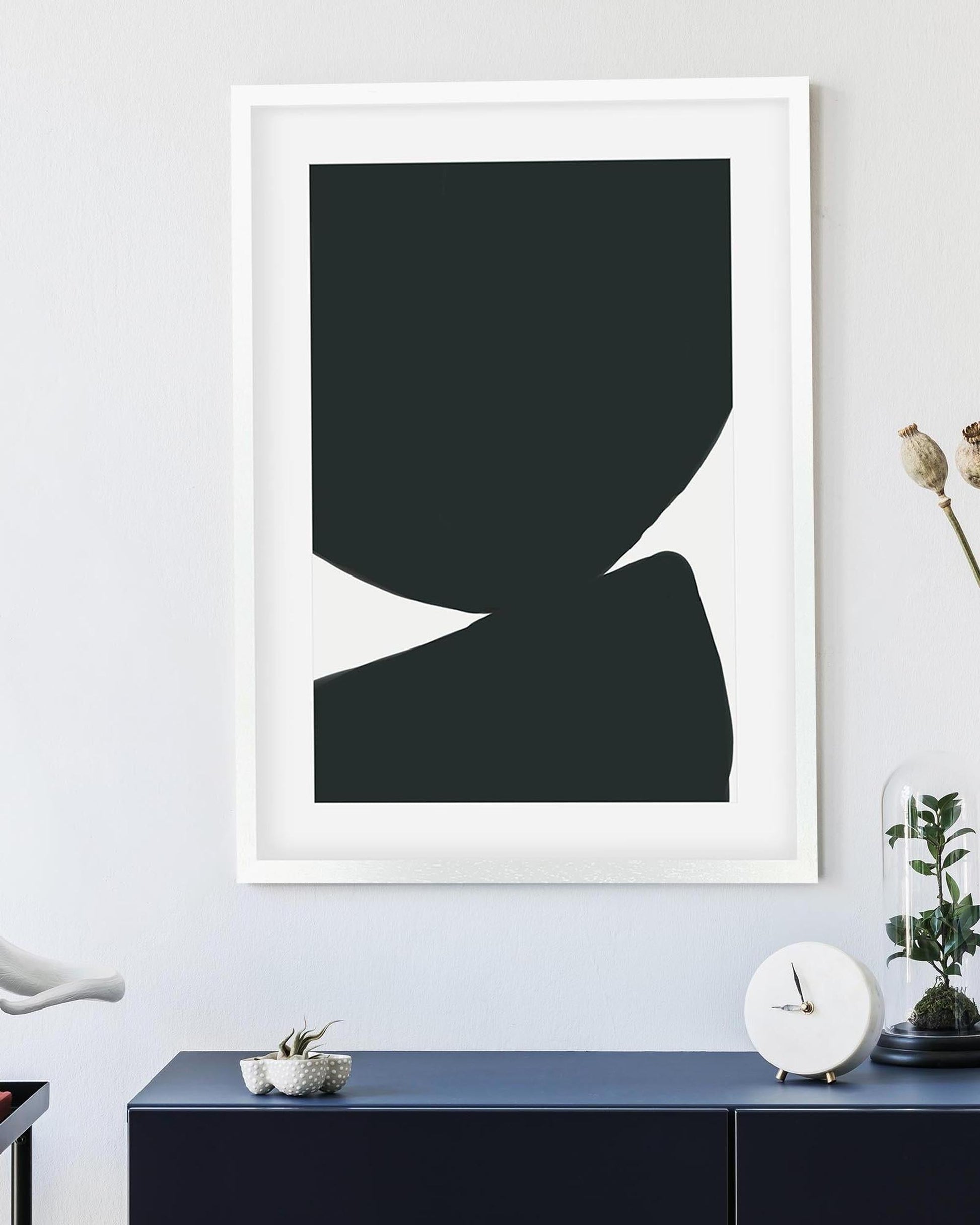 Framed abstract art piece on a wall with a blue console table below.