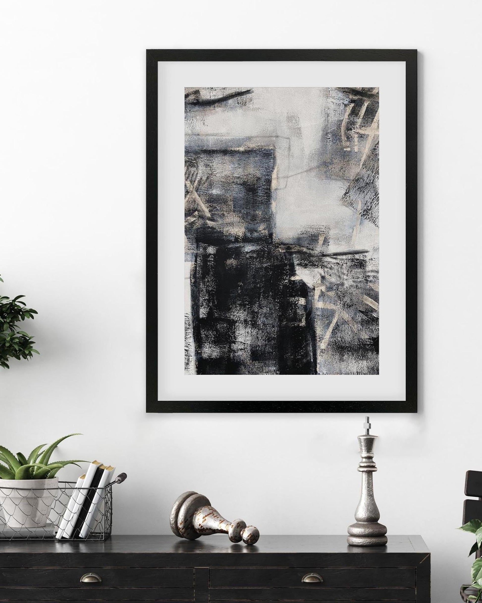 Framed abstract art piece on a wall above a black console table with decorative items.