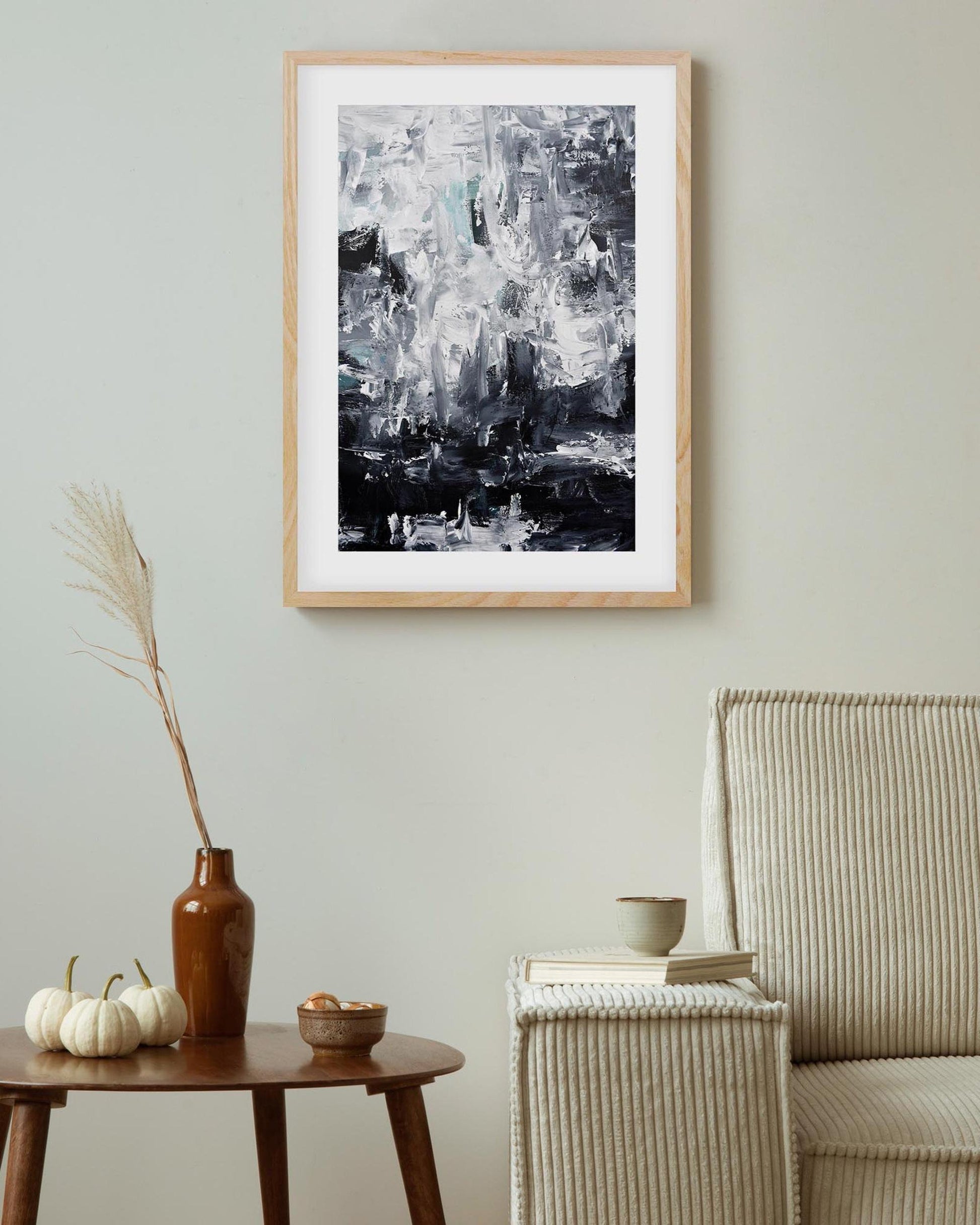 Abstract art print in a wooden frame on a wall above a table with decorative items.