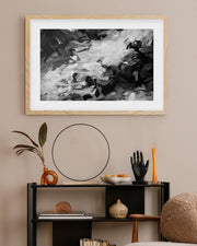 Framed abstract art above a shelf with decorative items on a beige wall.