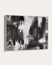 Abstract black and white painting in a gold frame on a white wall