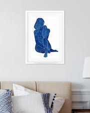 Framed artwork of a blue silhouette on a white wall above a bed.