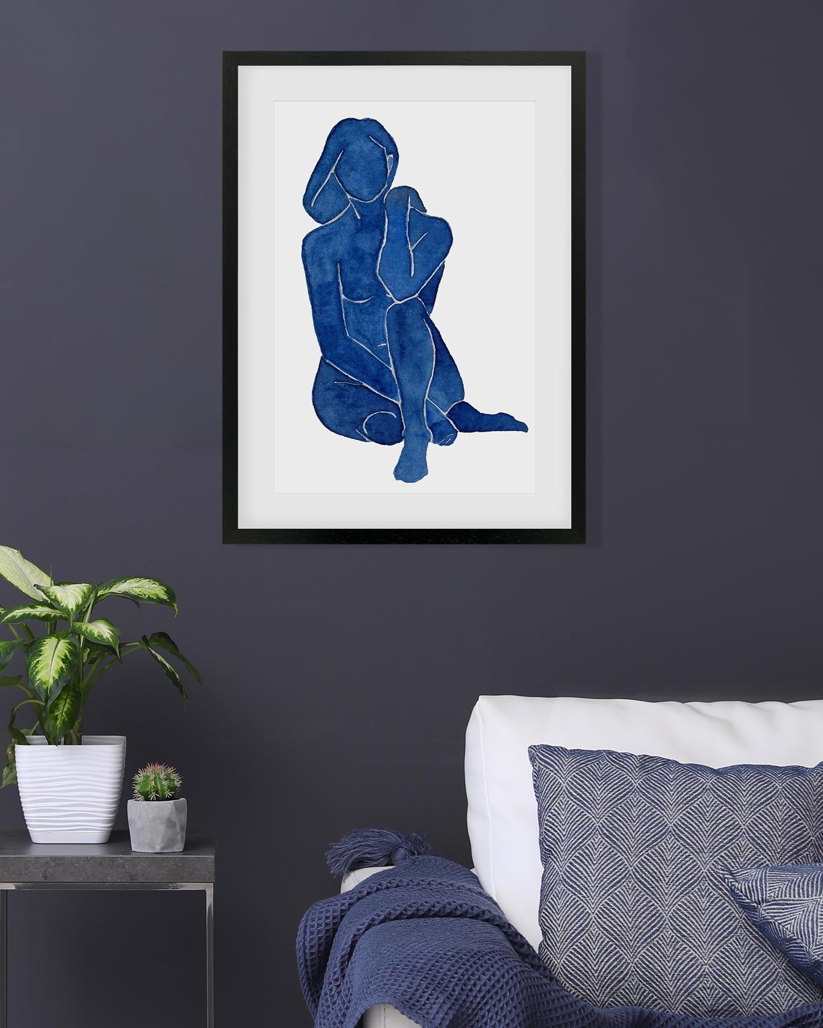 Framed abstract art of a blue figure on a white background, displayed in a living room.