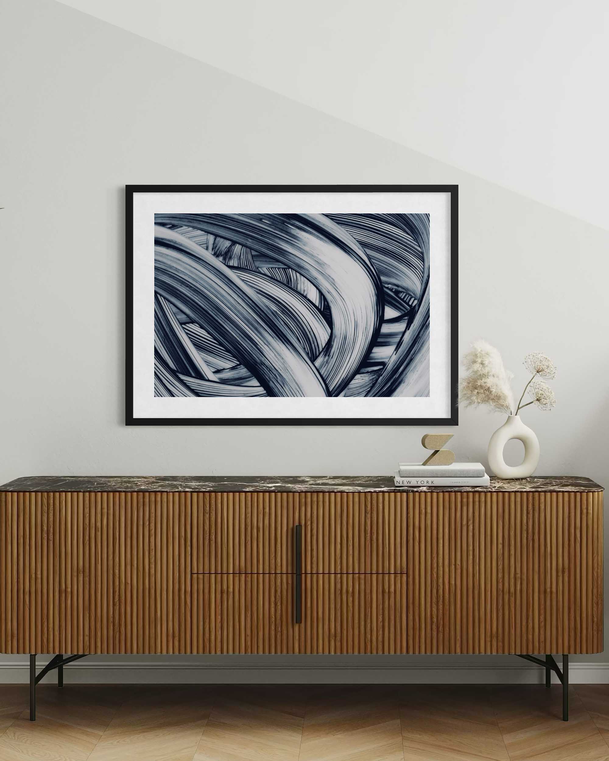 Framed abstract art above a wooden sideboard with decorative items.