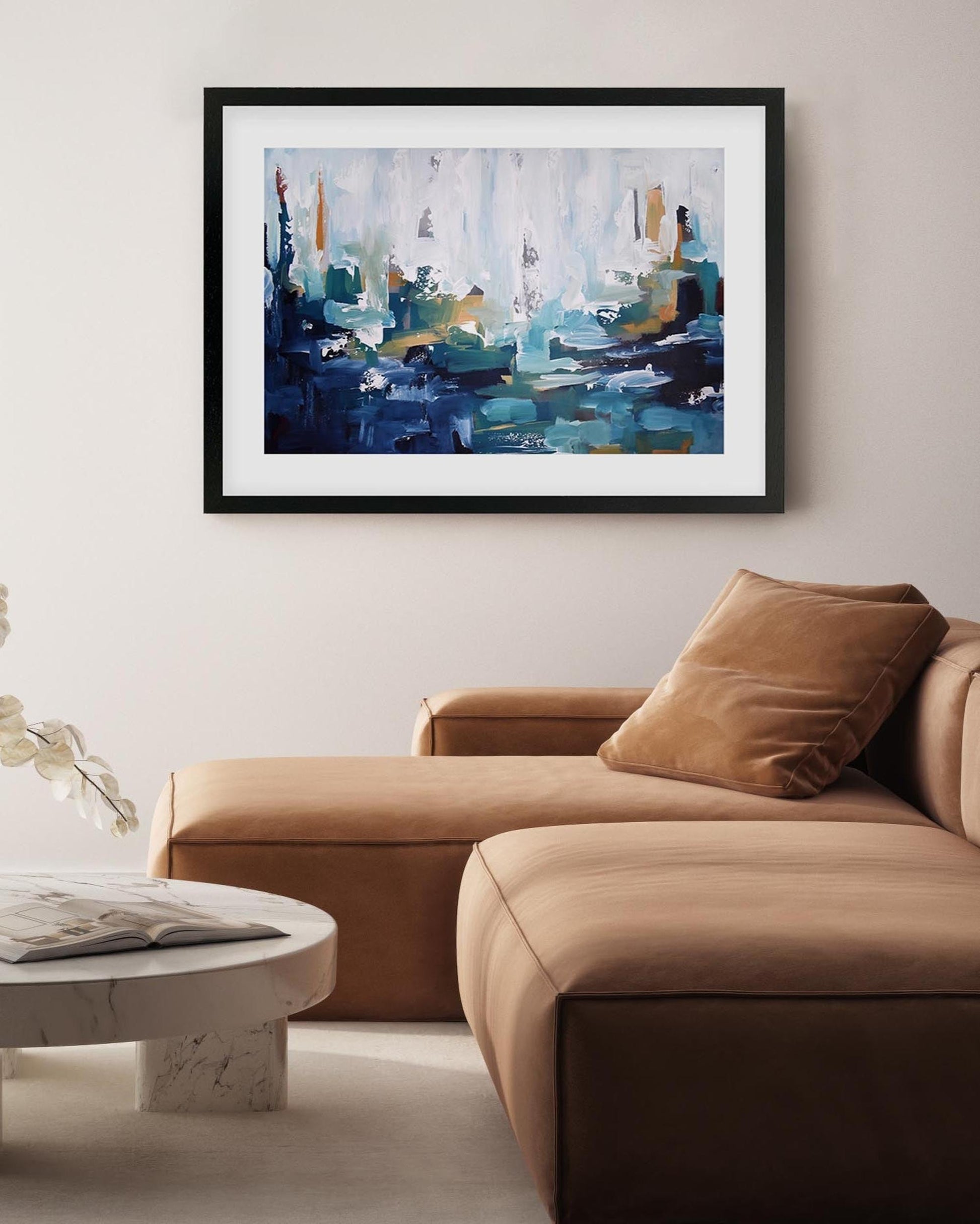 Abstract painting on a wall above a brown sofa in a living room.