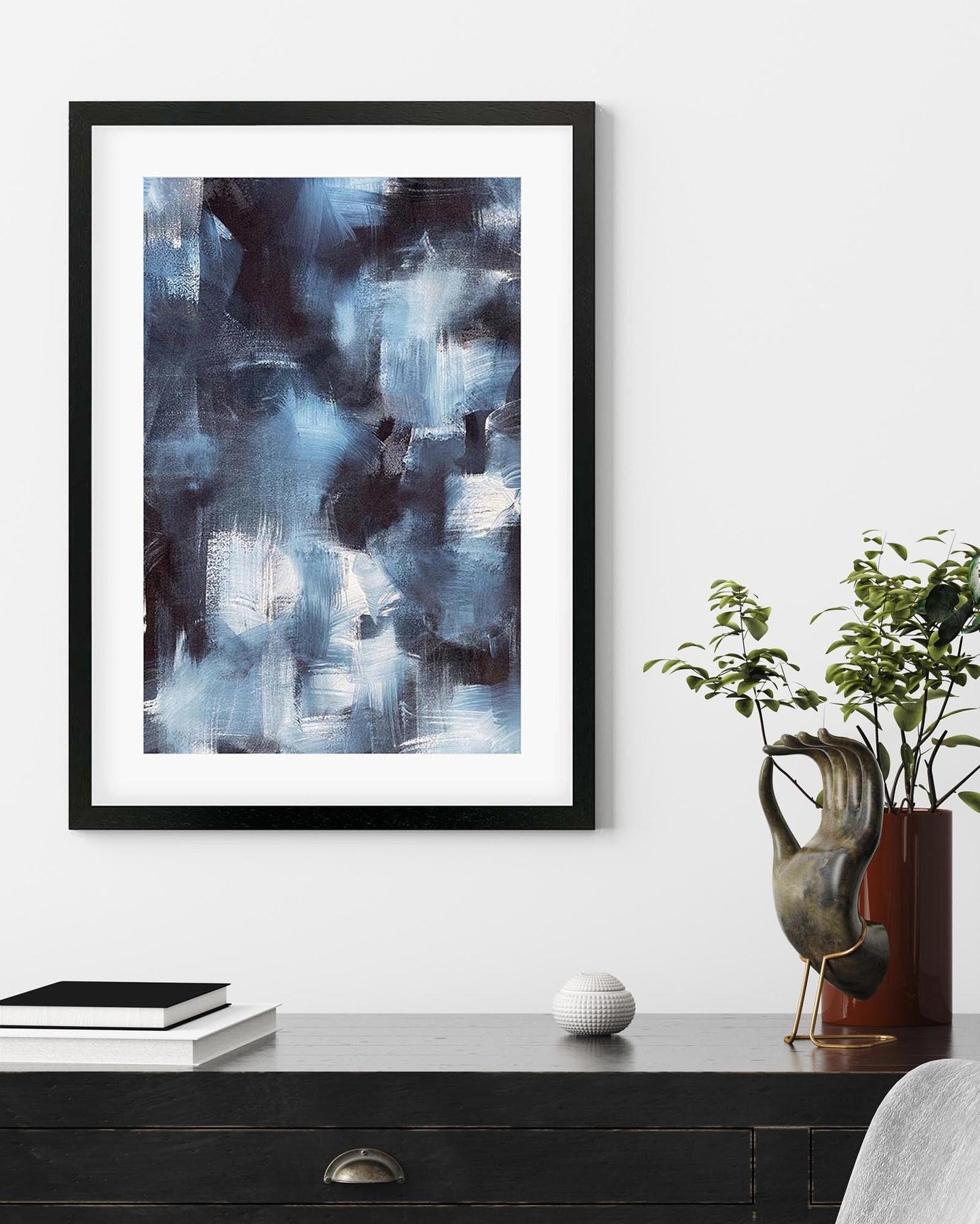 Framed abstract art piece on a wall above a desk with decorative items.