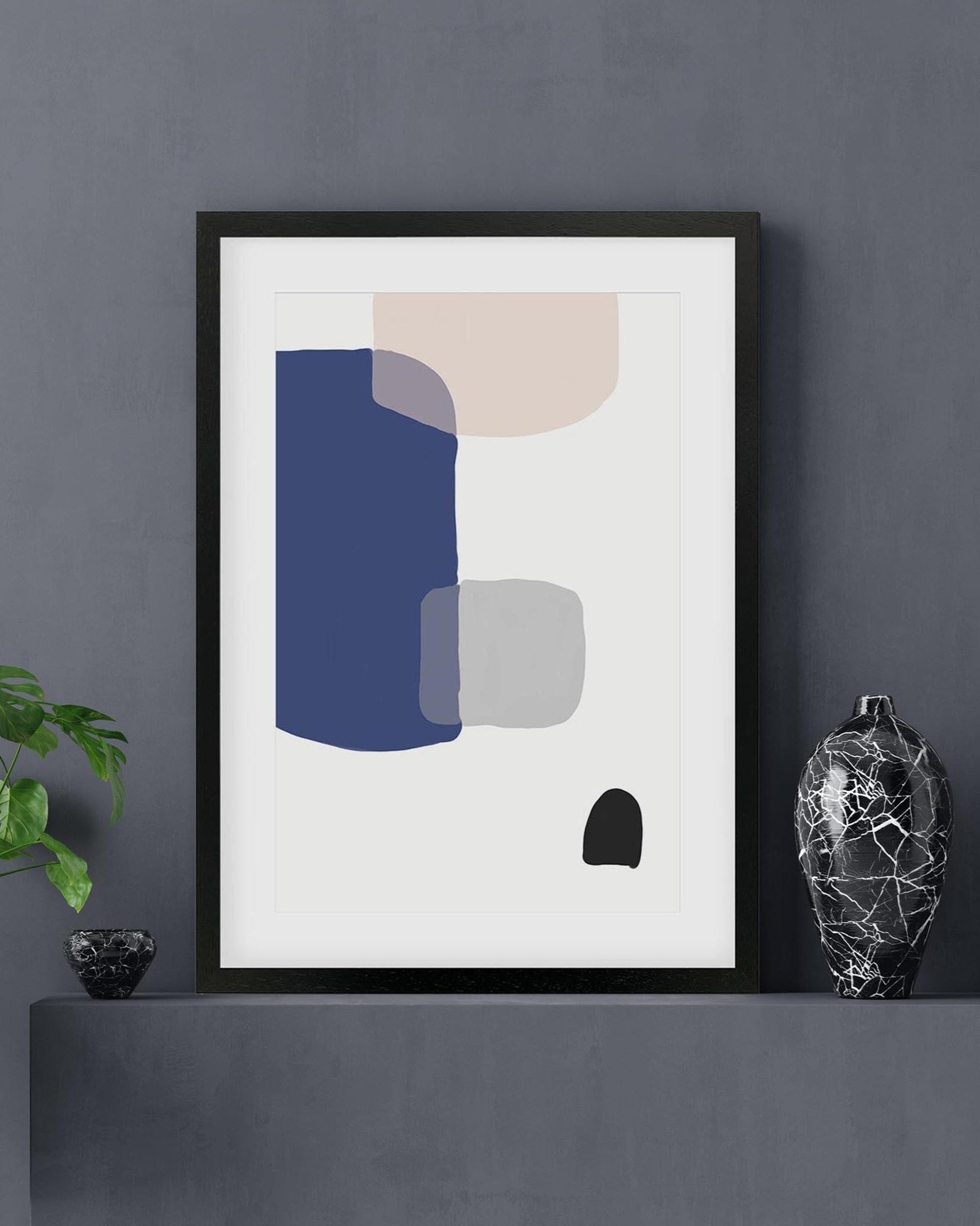 Framed abstract art print on a dark gray wall with decorative items.