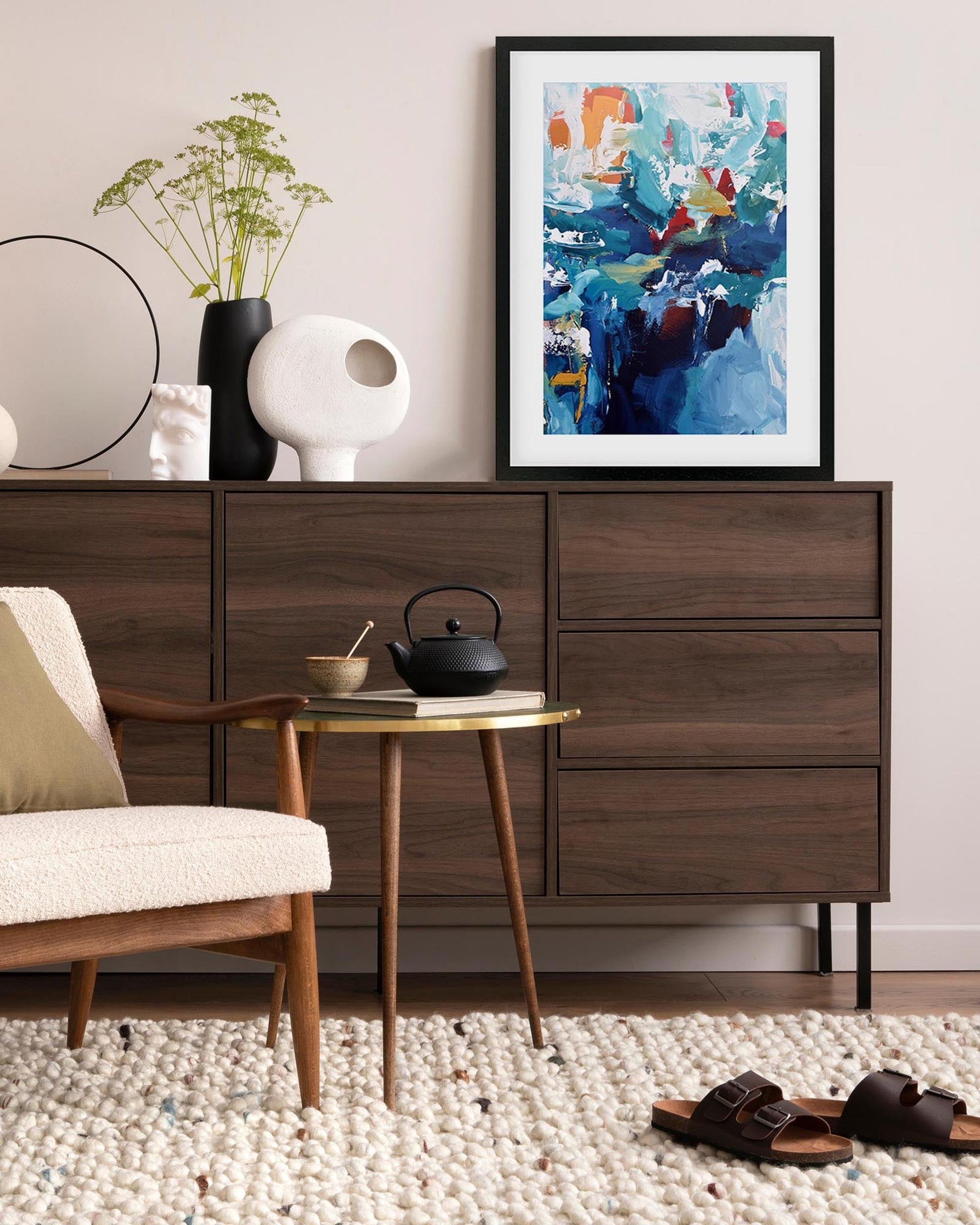Modern living room with wooden dresser, side table, and abstract art