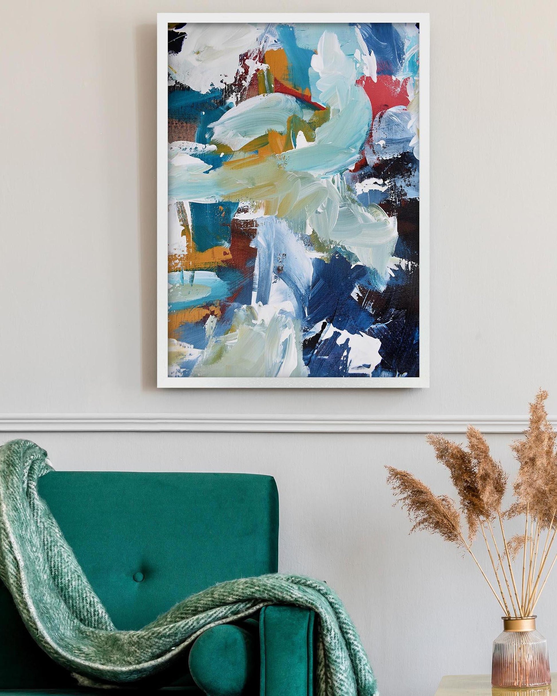 Abstract painting on a wall above a teal chair with a decorative plant.