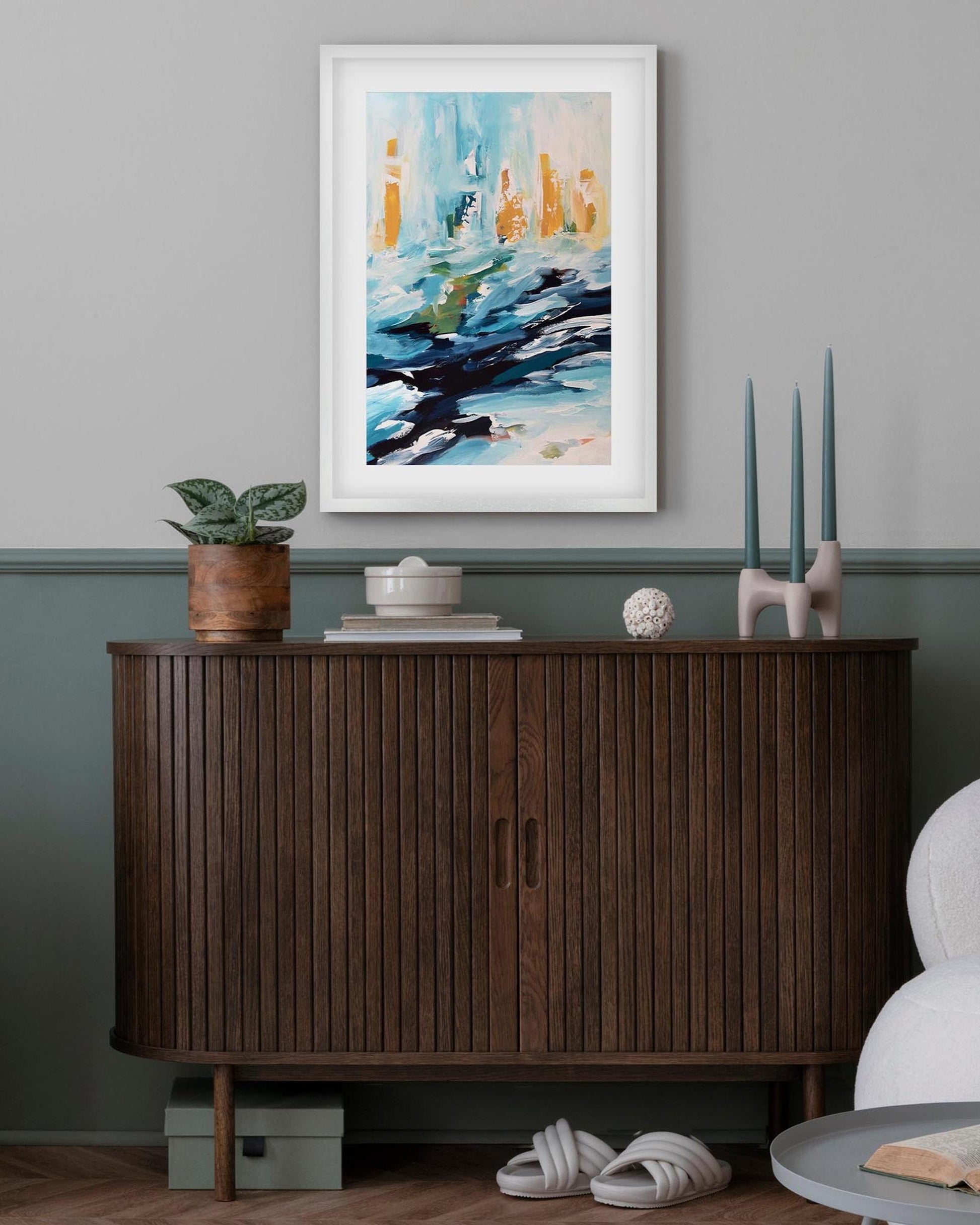 Living room with wooden sideboard, white sofa, and framed abstract art on gray wall.