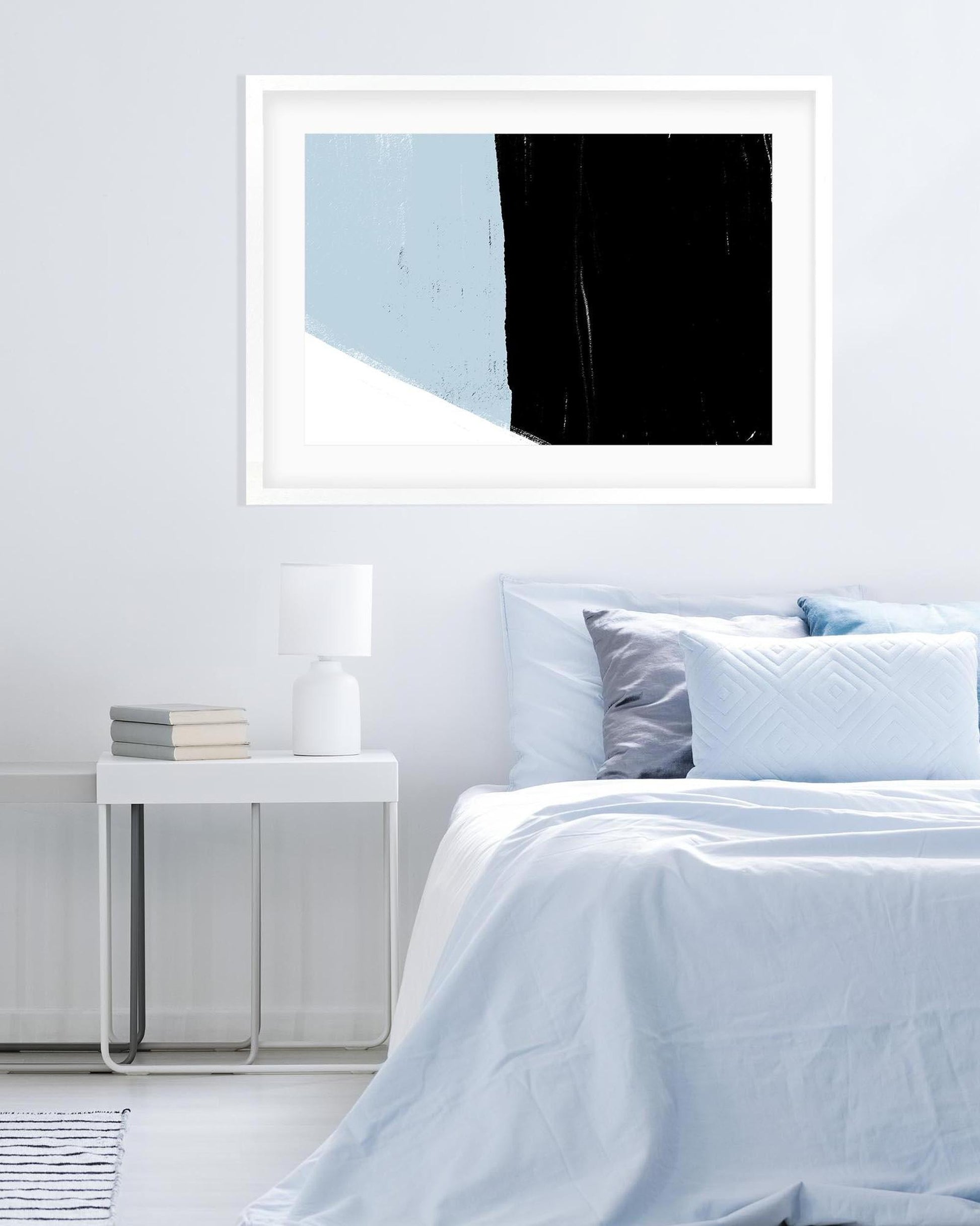 Framed abstract art above a bed in a bedroom setting