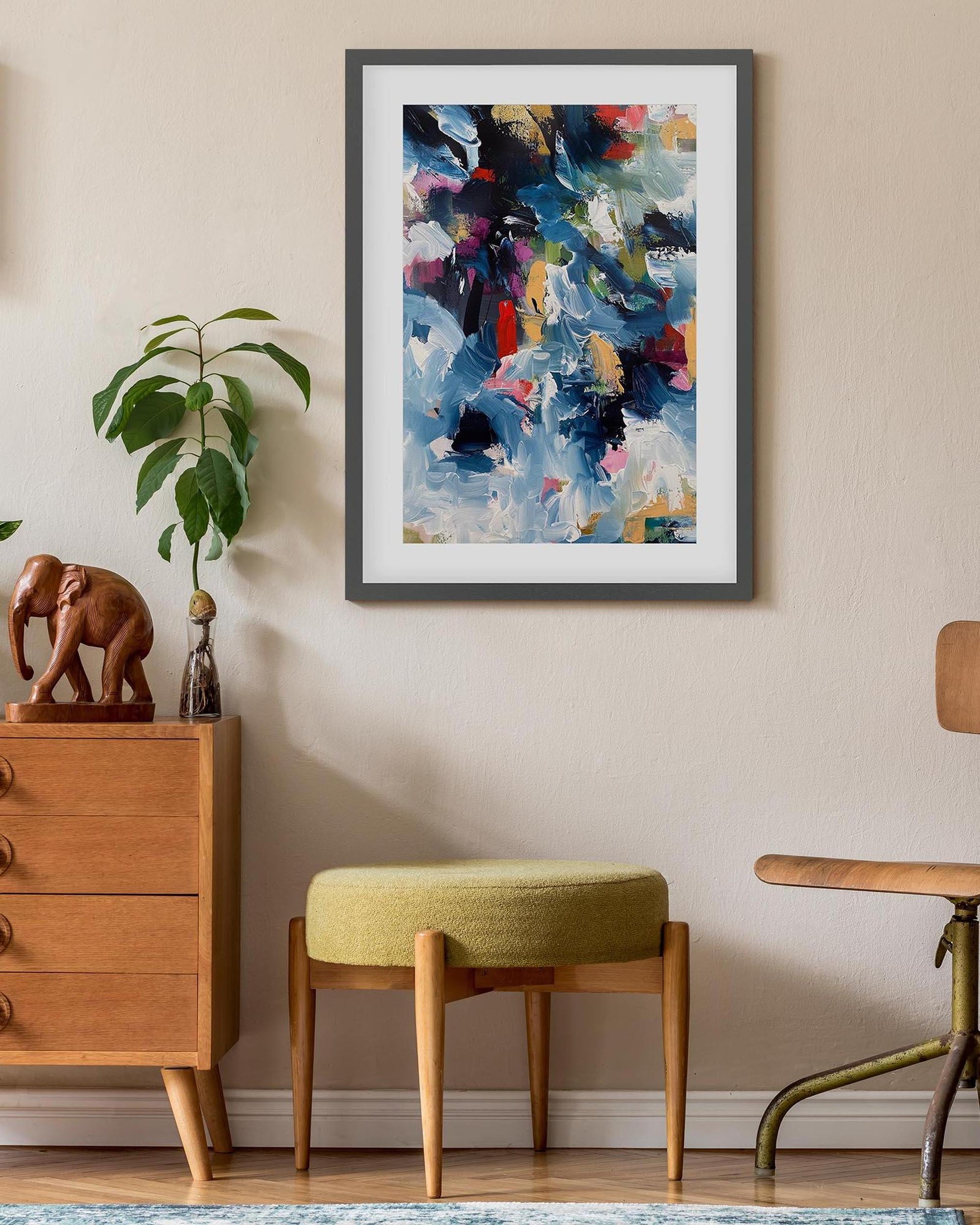 Framed abstract art piece on a wall with wooden furniture and decor items.