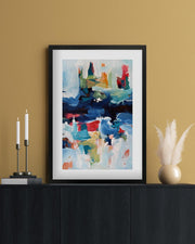 Framed abstract painting on a wall above a black cabinet with decorative items.