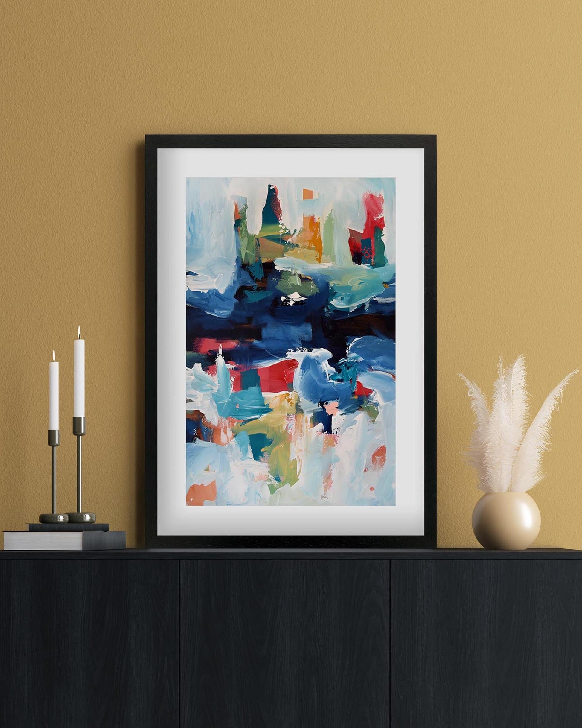 Framed abstract painting on a wall above a black cabinet with decorative items.