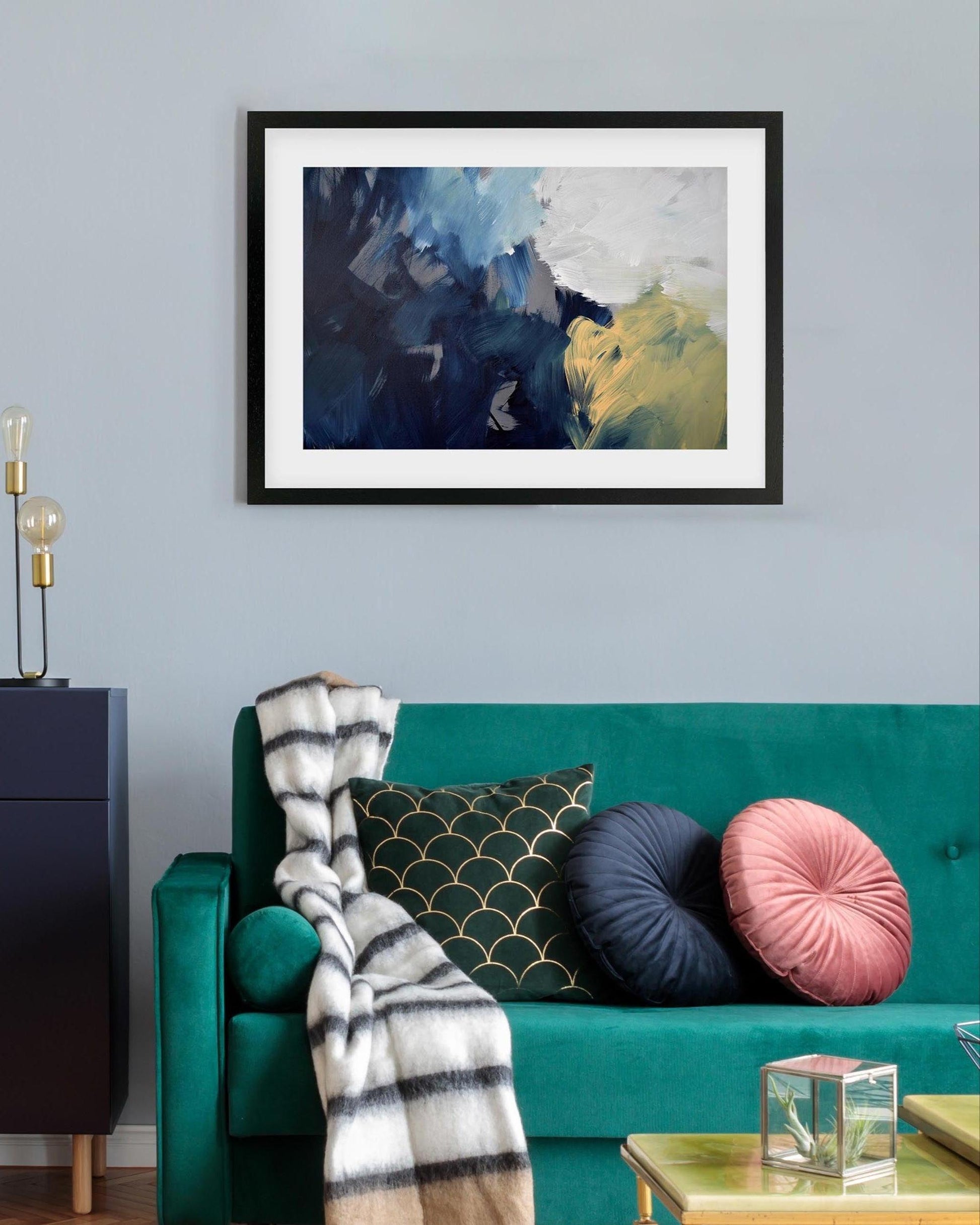 Living room with teal sofa, abstract art on wall, and sideboard.