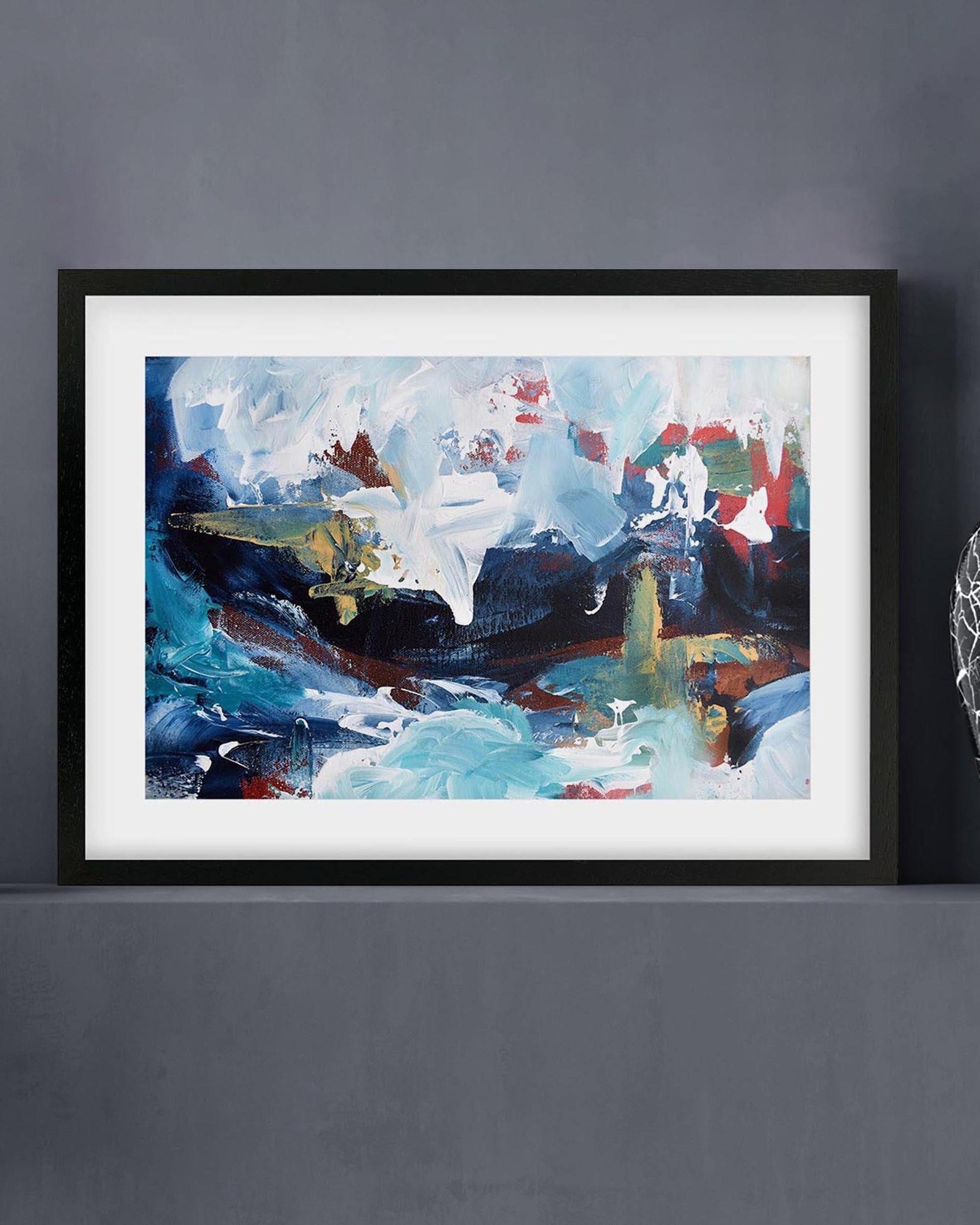 Framed abstract painting with colorful brush strokes on a gray wall