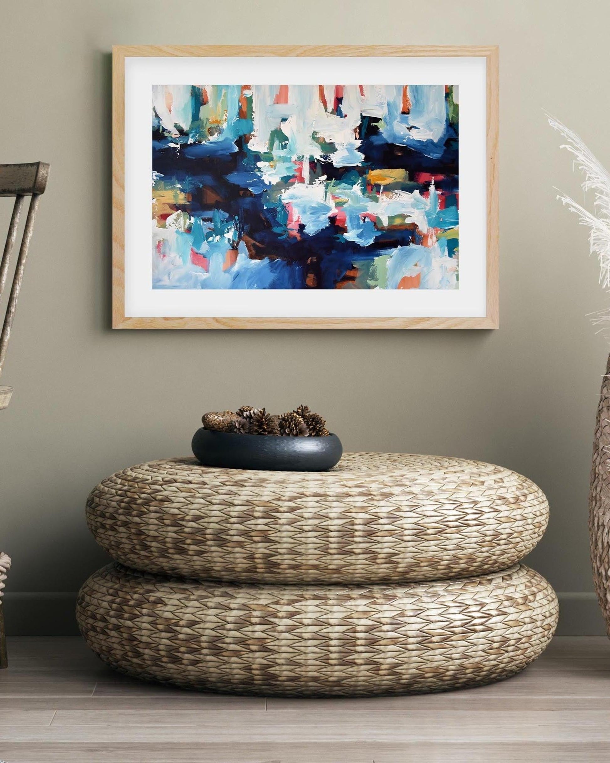 Living room with a wicker ottoman, abstract painting, and decorative items.