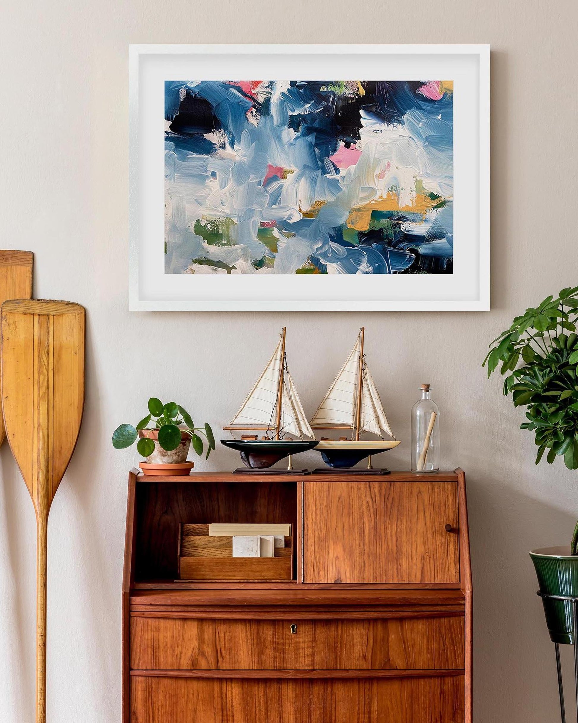 Abstract painting on a wall above a wooden cabinet with decorative items.