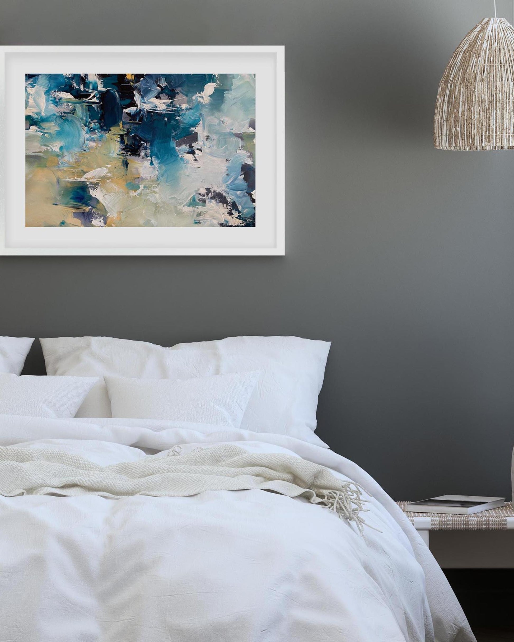 Framed abstract art above a bed with white bedding and a dark gray wall.