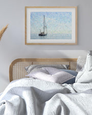 Framed artwork of a sailboat on a wall above a bed with white bedding.