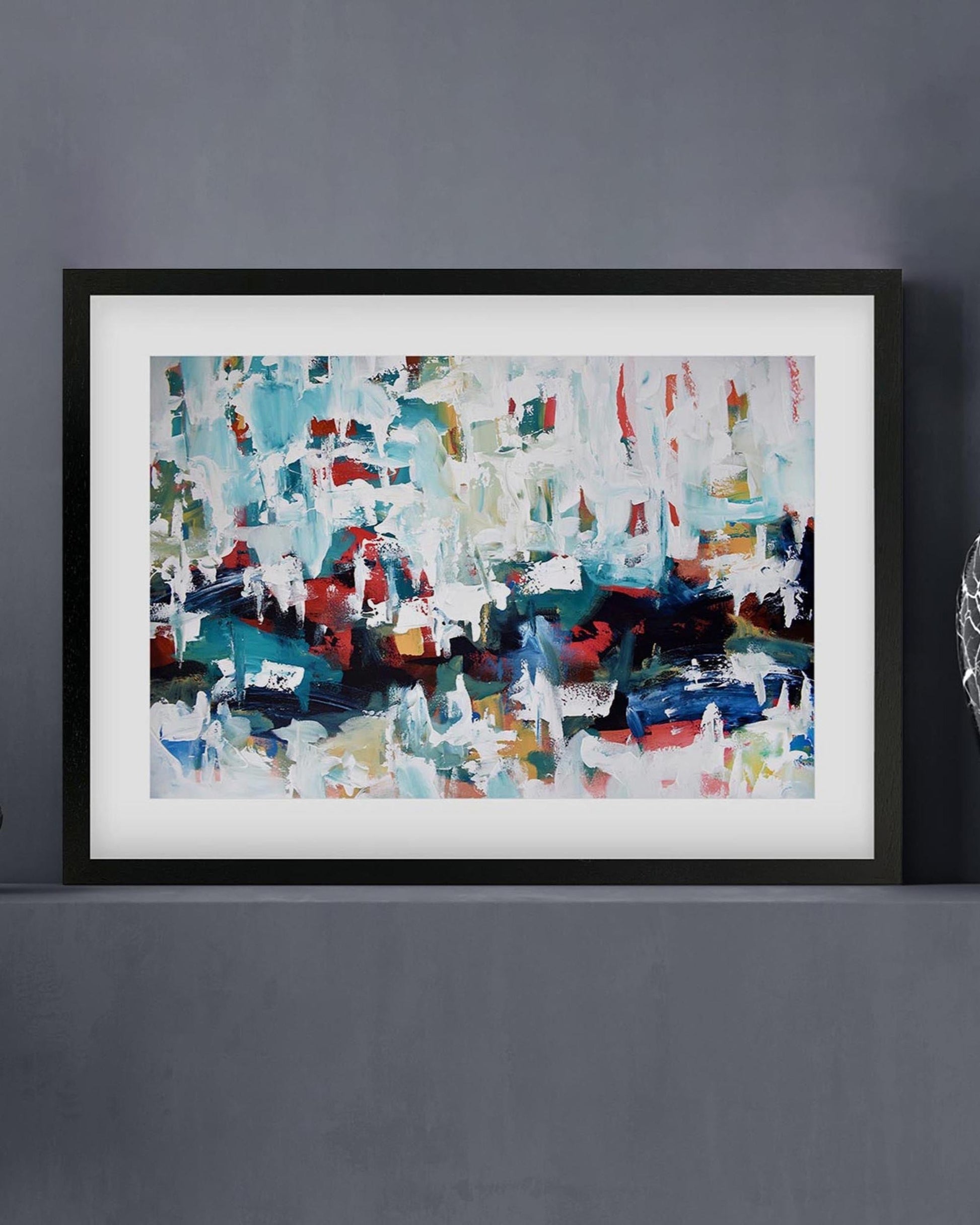 Framed abstract painting with multicolors on a gray wall