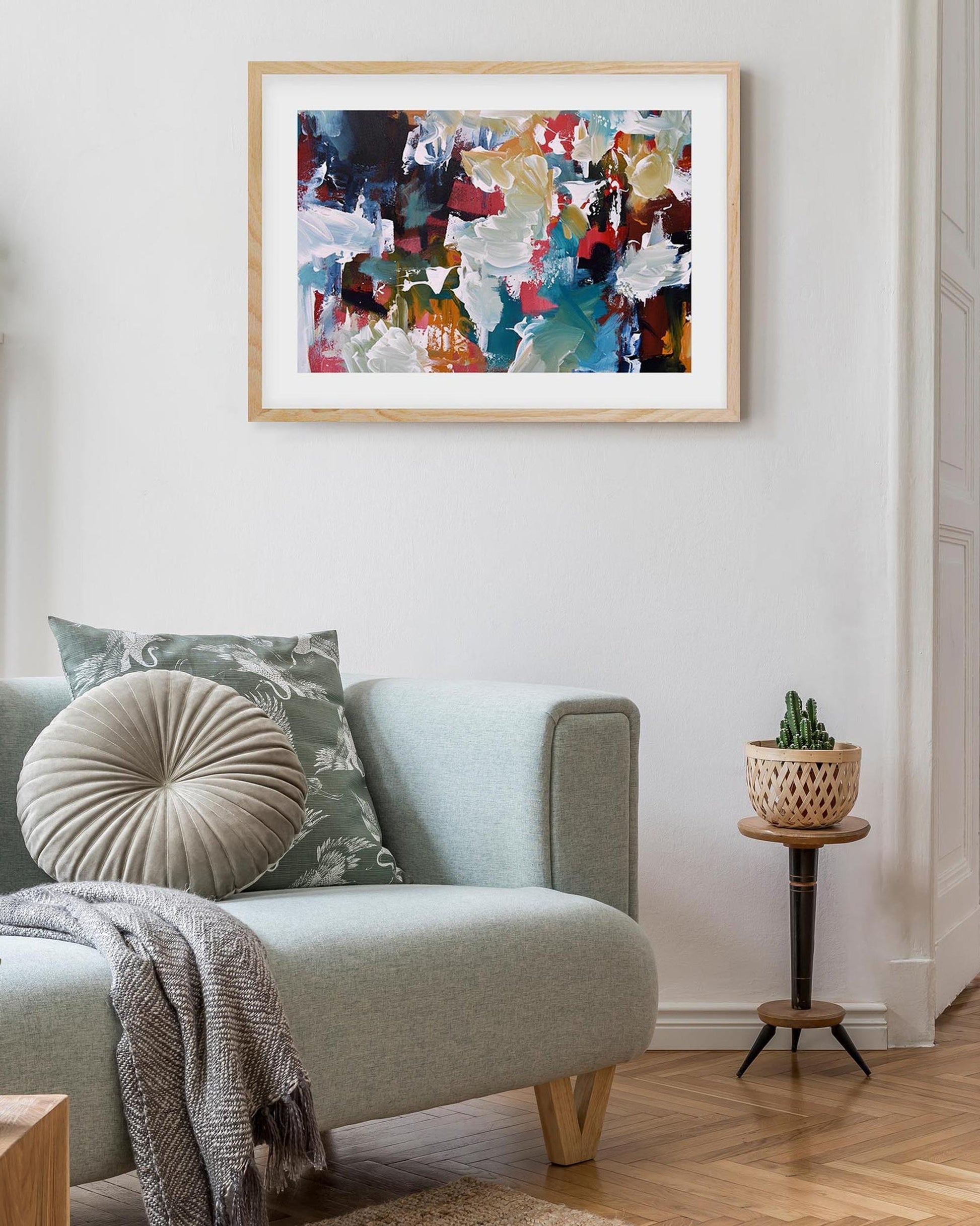 Living room with a gray sofa, decorative pillows, and a colorful abstract painting on the wall.