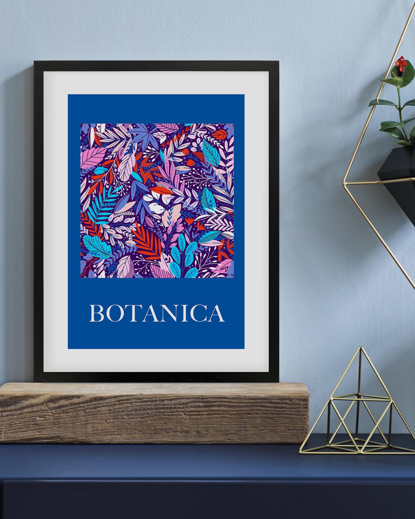 Framed artwork with colorful leaf pattern and 'BOTANICA' text on a blue background, displayed on a shelf.