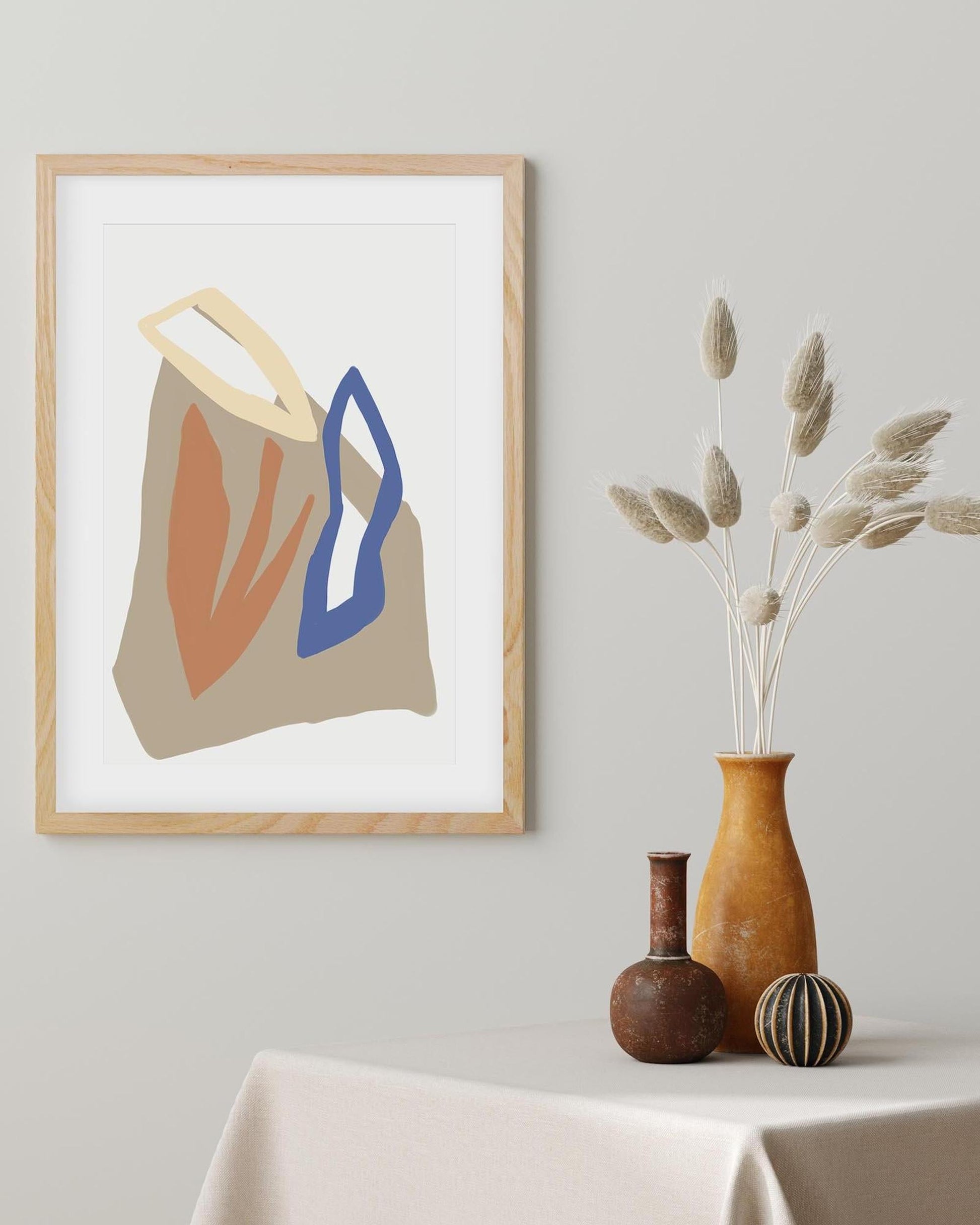 Framed abstract art print on a wall with decorative vases below.