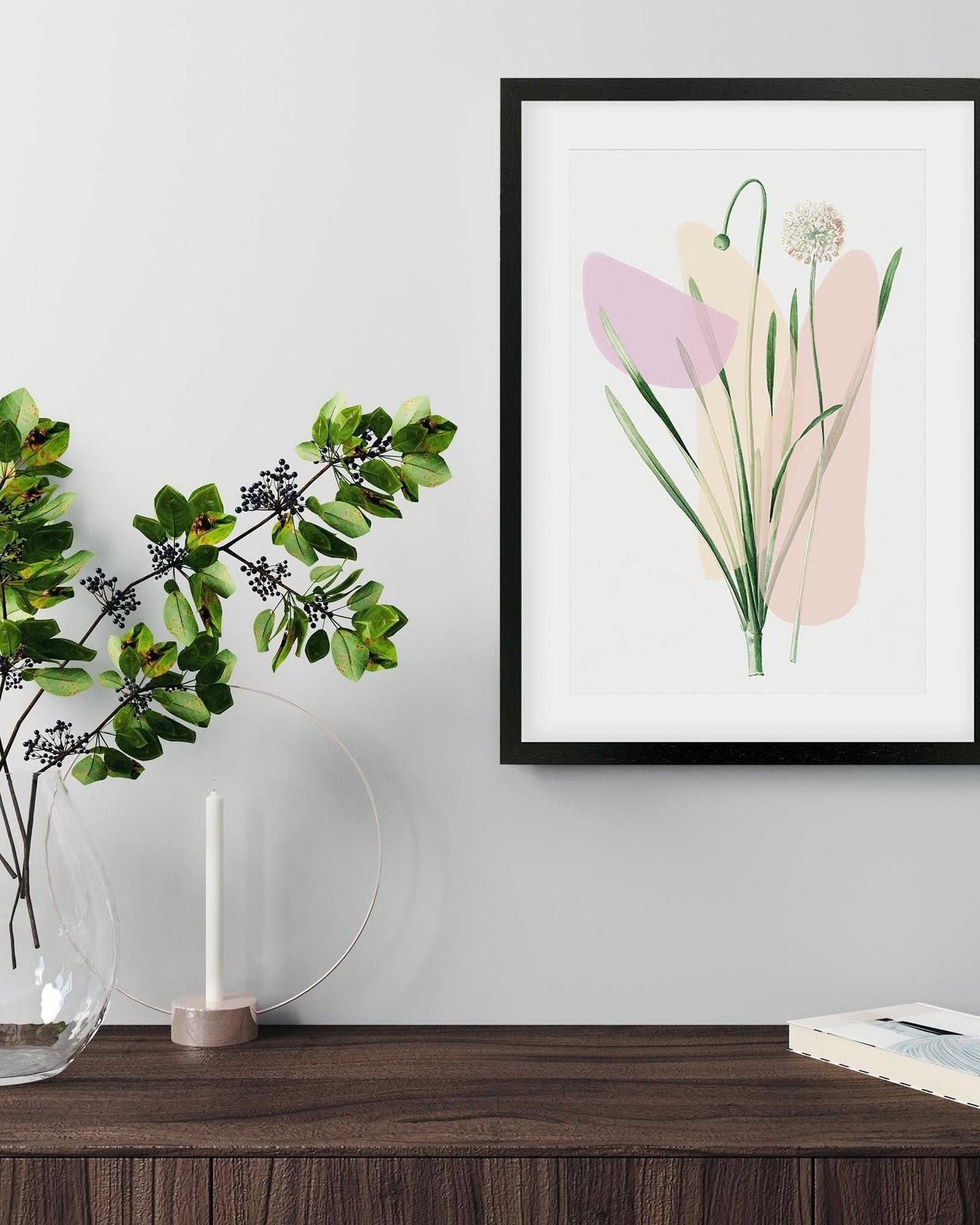 Framed abstract floral art on a wall above a wooden surface with a vase and candle.