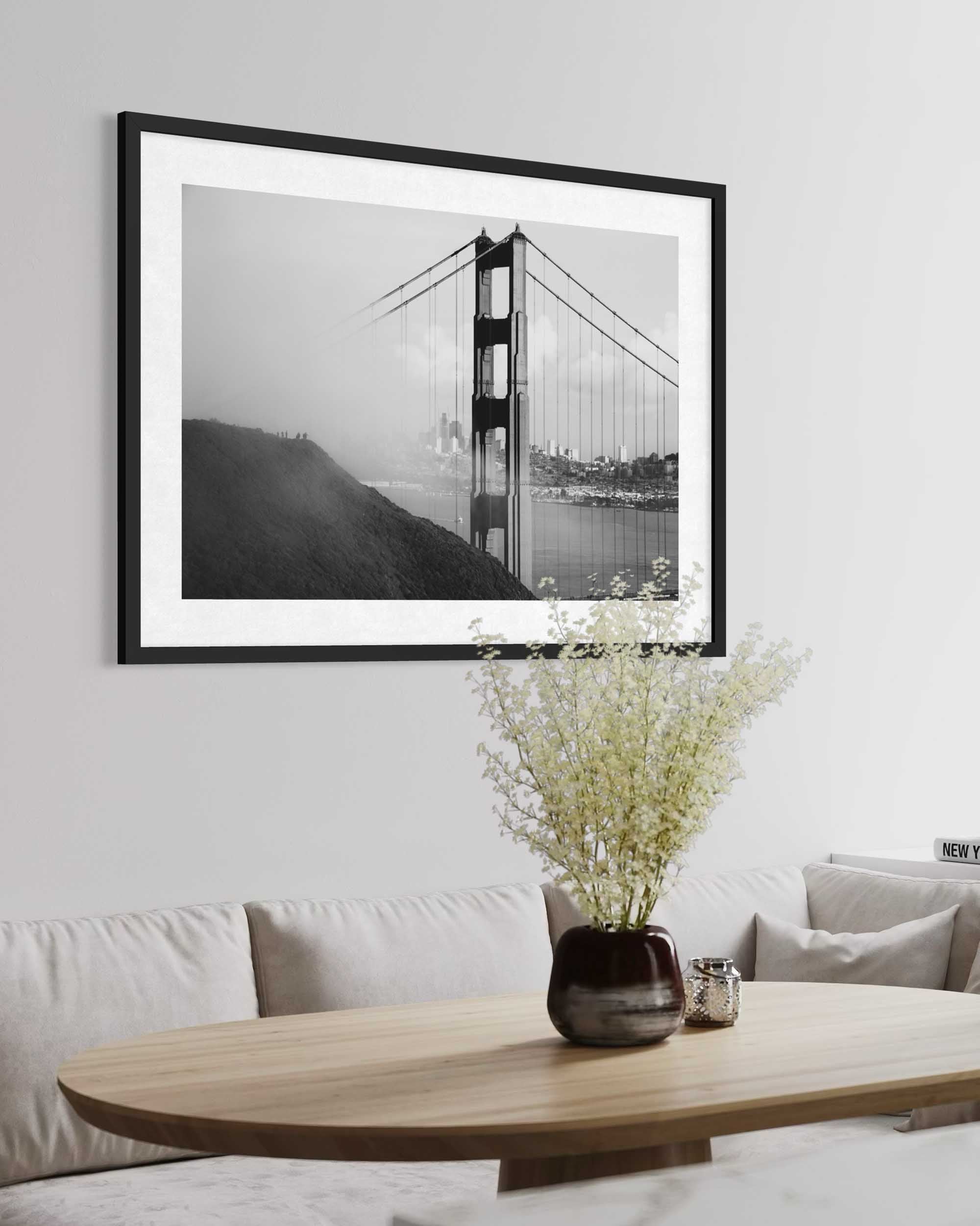 Framed black and white photograph of a suspension bridge on a wall above a sofa and coffee table.