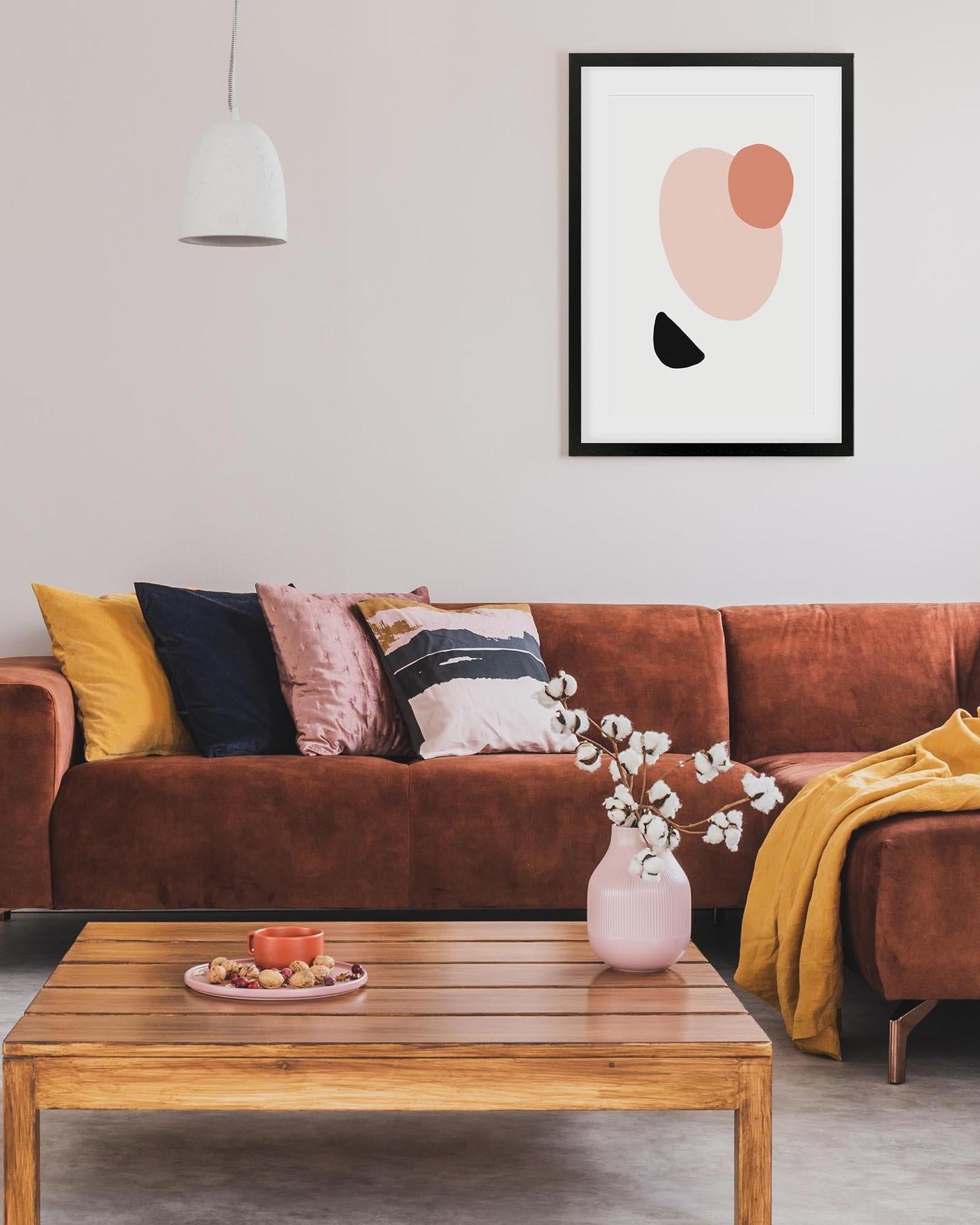 Living room with a brown sofa, wooden coffee table, and abstract art on the wall.