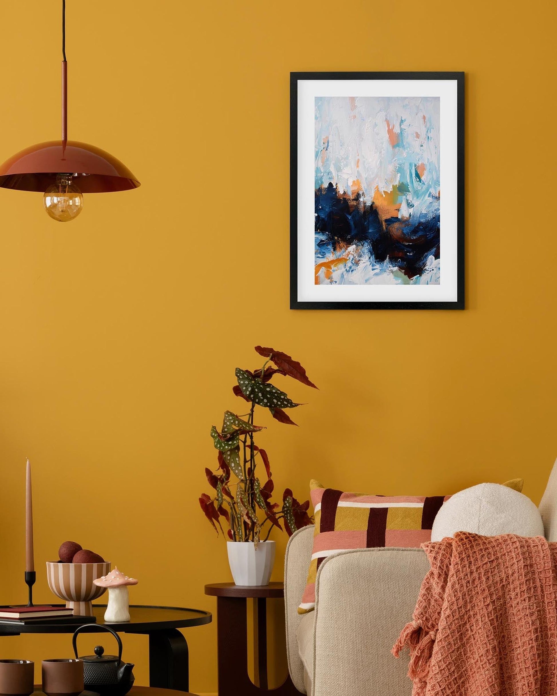 Living room with yellow walls, a framed abstract painting, and decorative items.
