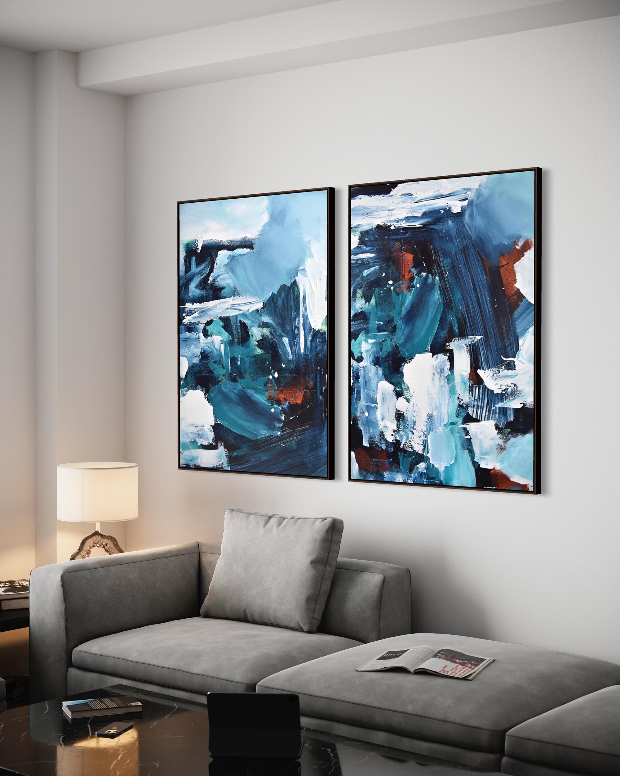 Two abstract paintings on a wall above a gray sofa in a living room.