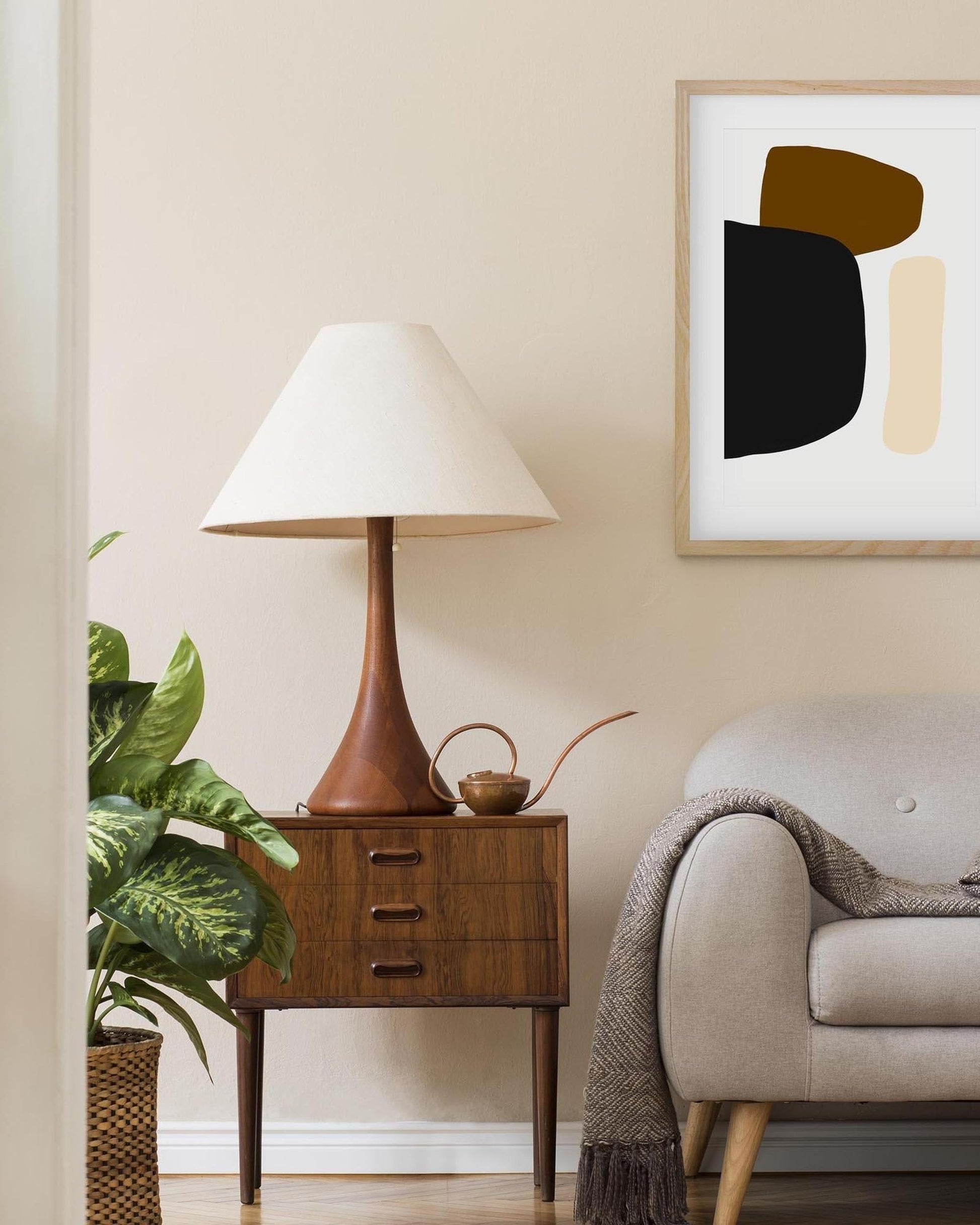 Nestled corner of a living room with a wooden side table, lamp, and abstract art on the wall.