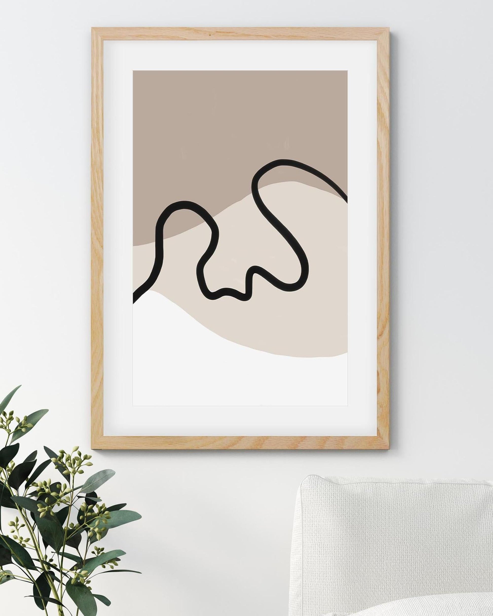 Framed abstract art print with wavy line design on a beige background, placed on a white wall.