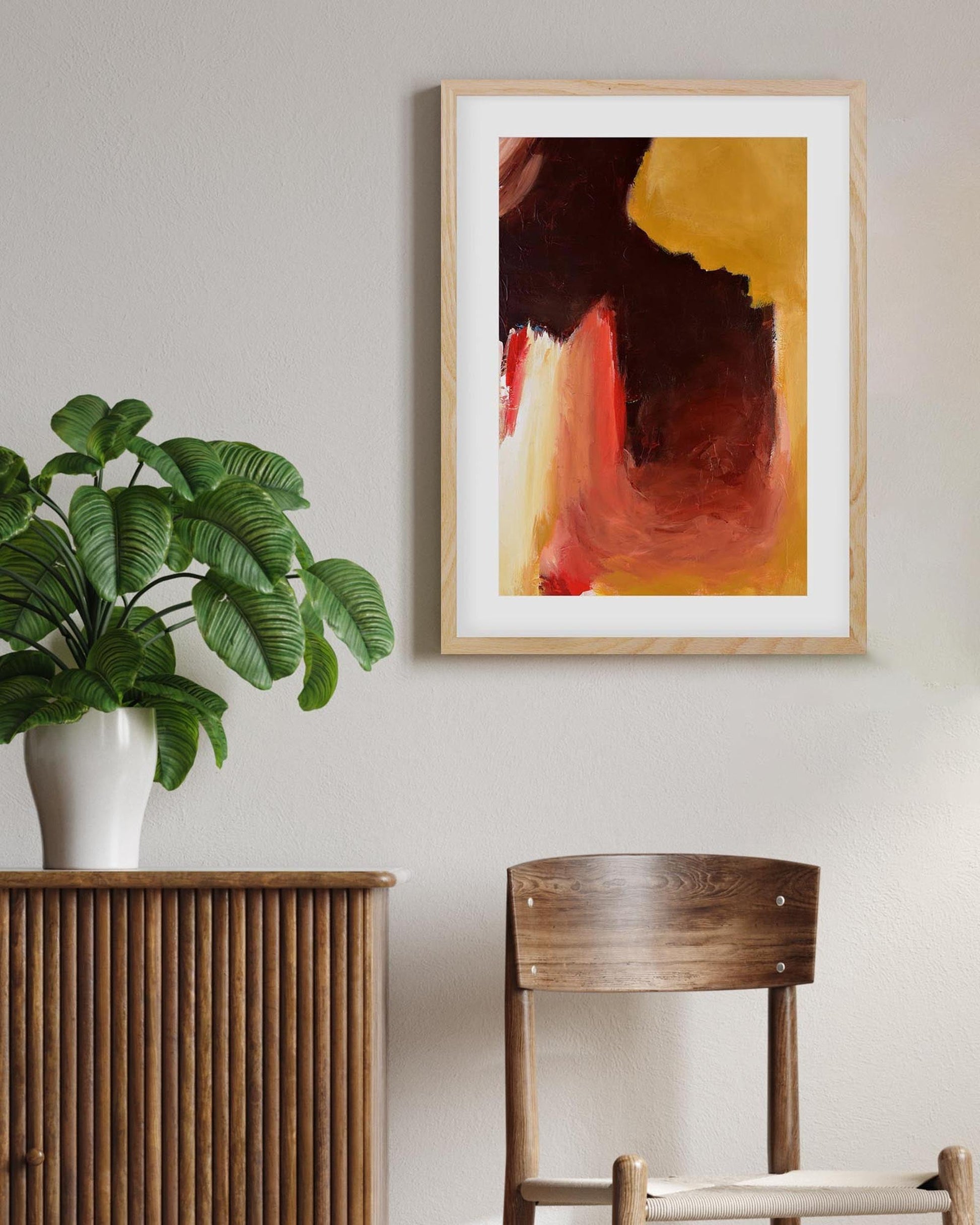 Room interior with a plant on a wooden sideboard, a chair, and abstract art on the wall.