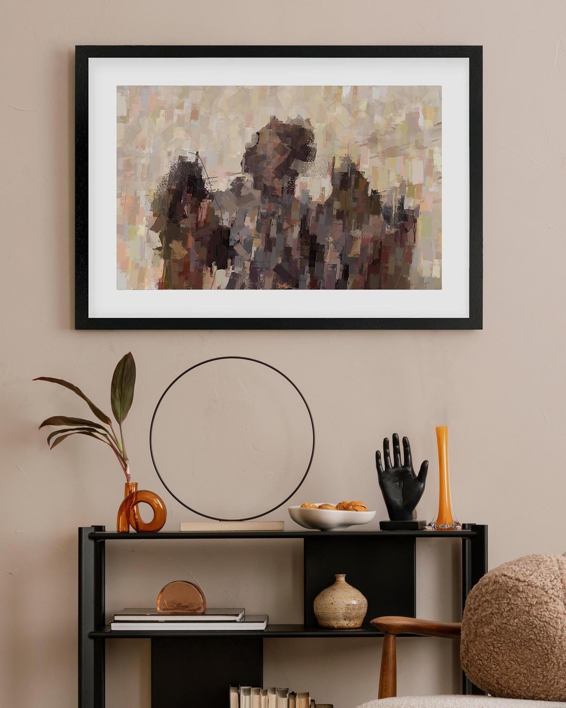 Framed abstract art piece on a wall above a shelf with decorative items.
