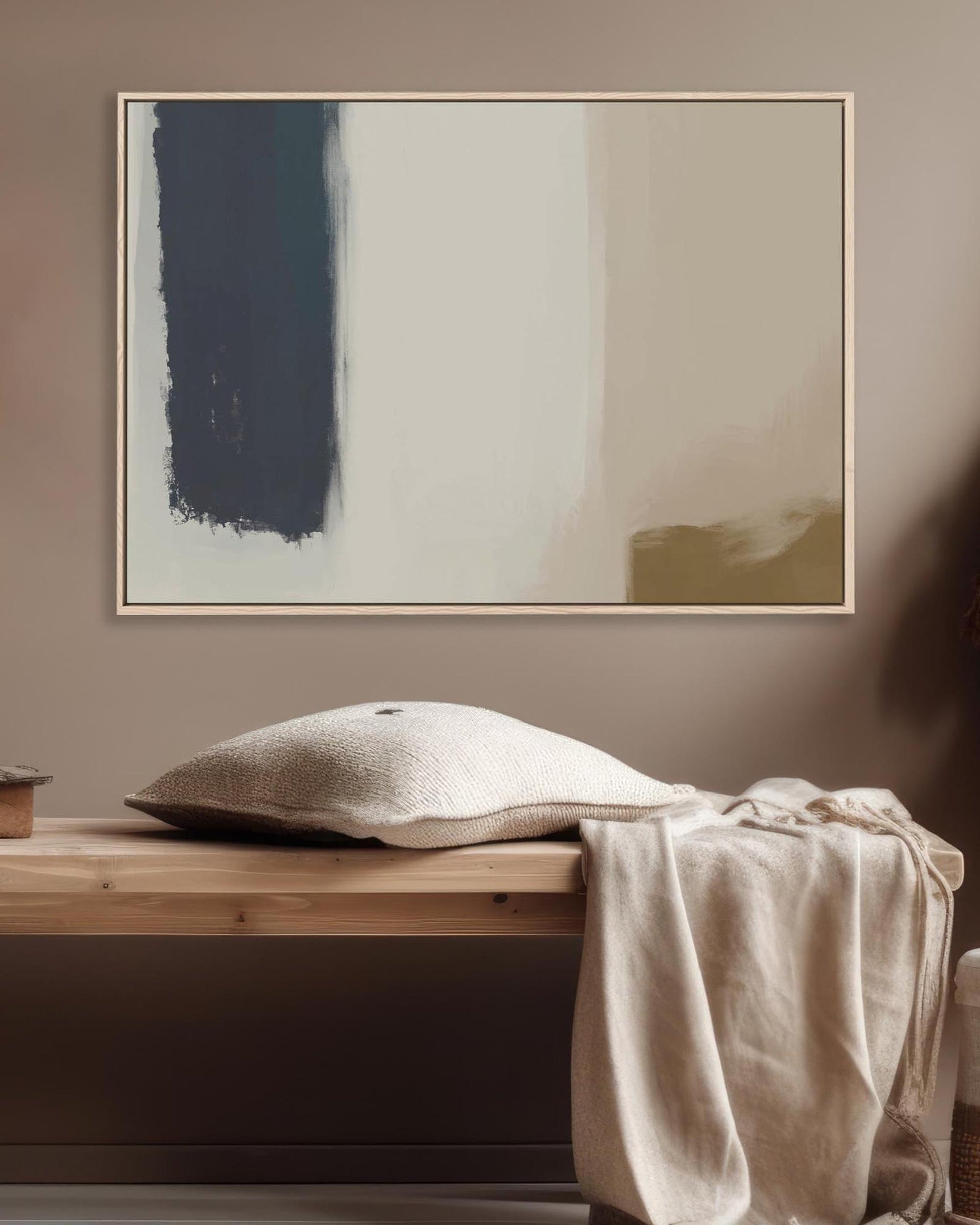 Abstract painting on a wall above a wooden bench with a pillow and blanket.