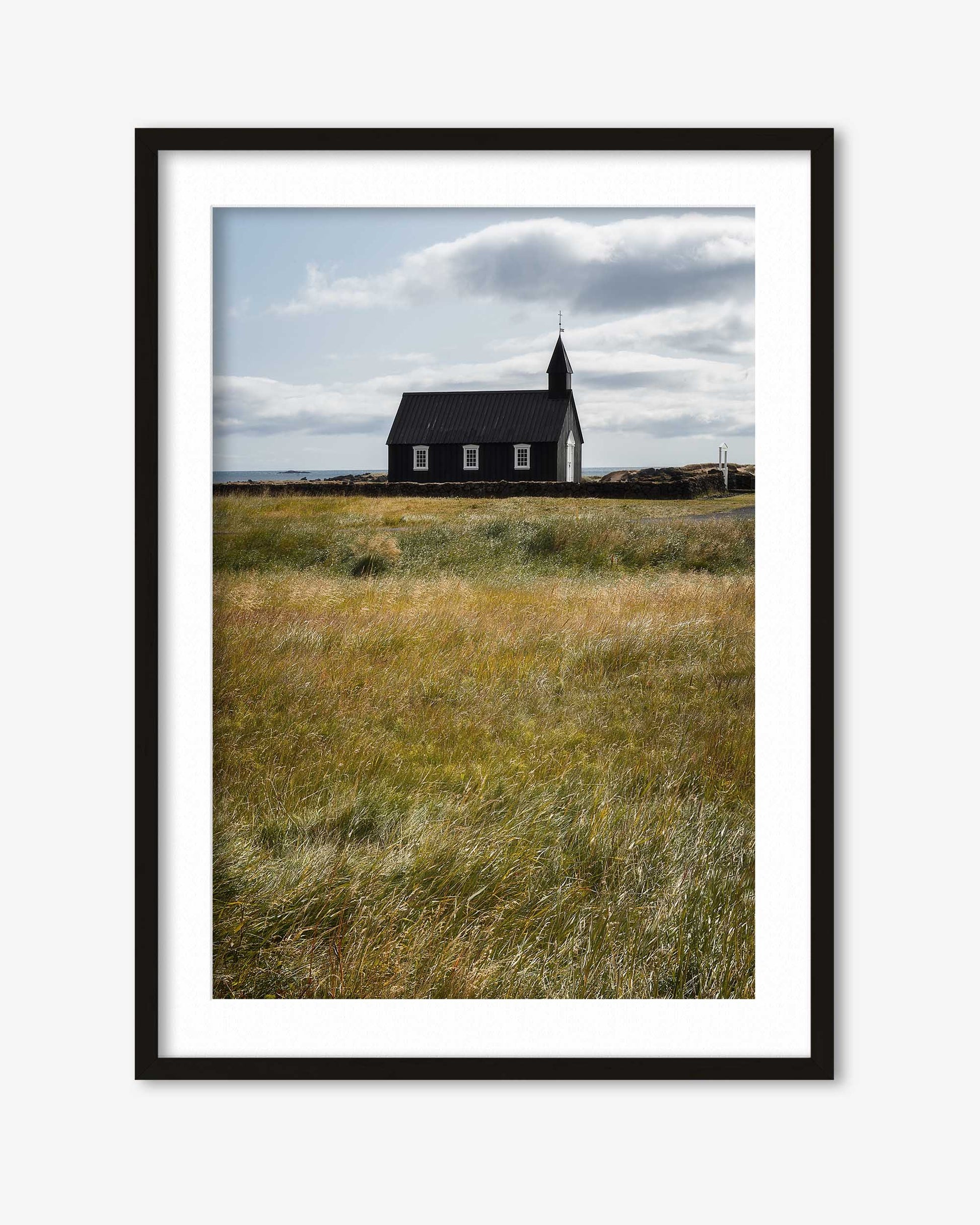 Framed photograph of a church in a field with a cloudy sky