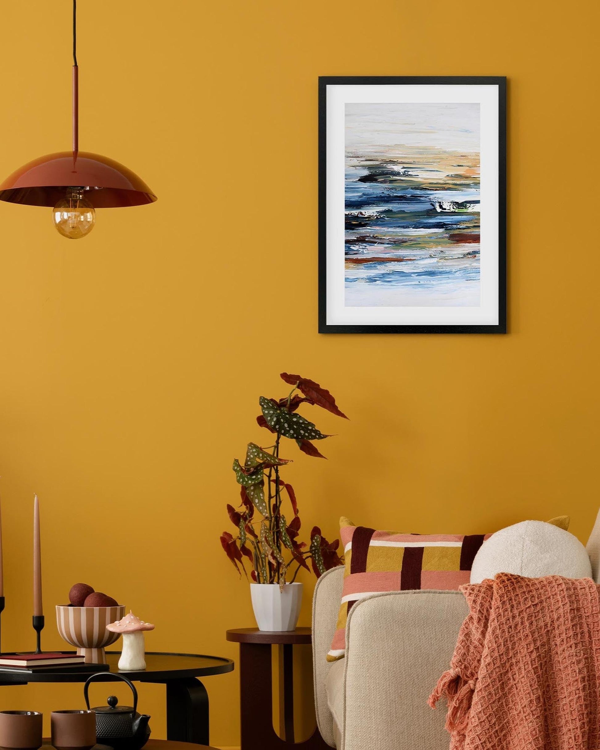 Living room with a yellow wall, framed abstract art, and decorative elements.