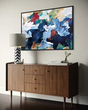 Wooden sideboard with a lamp and abstract painting on a wall