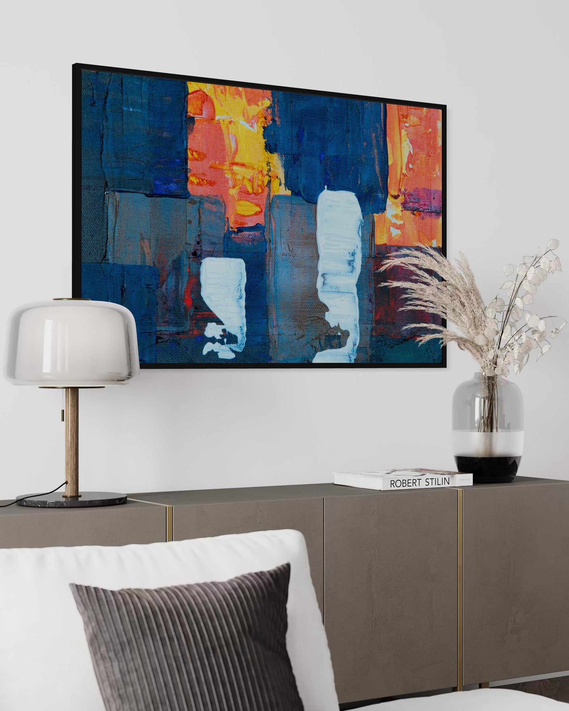 Modern living room with abstract art, lamp, and decorative elements.