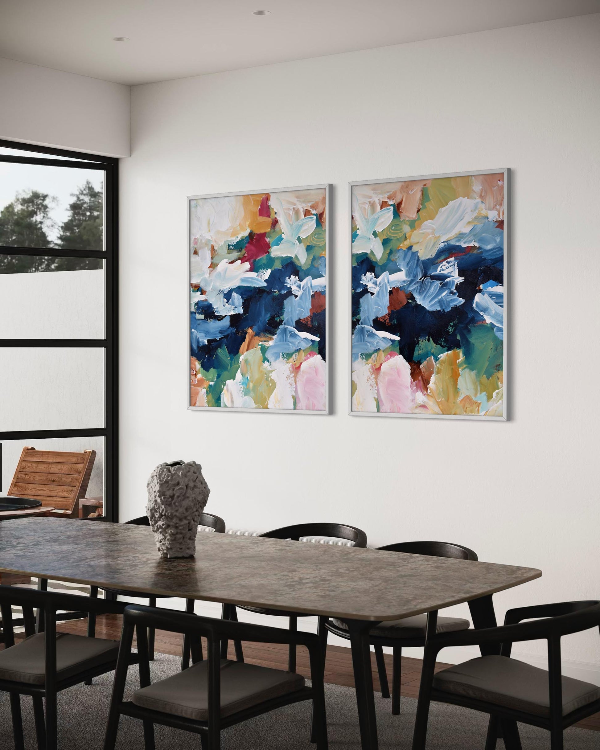 Dining room with two abstract art pieces on the wall above a table.