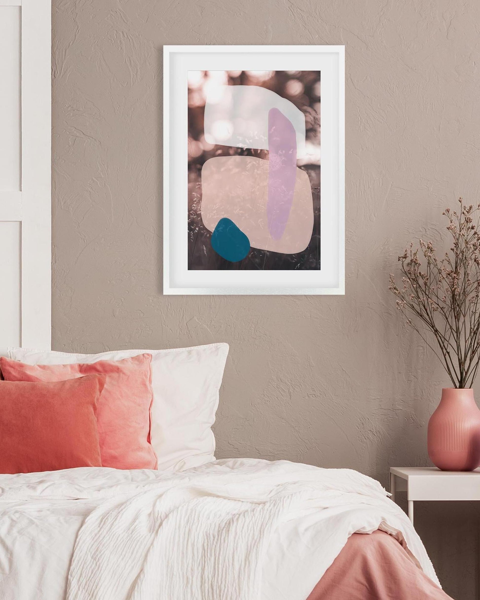 Abstract art print on a wall above a bed with pink and white bedding.